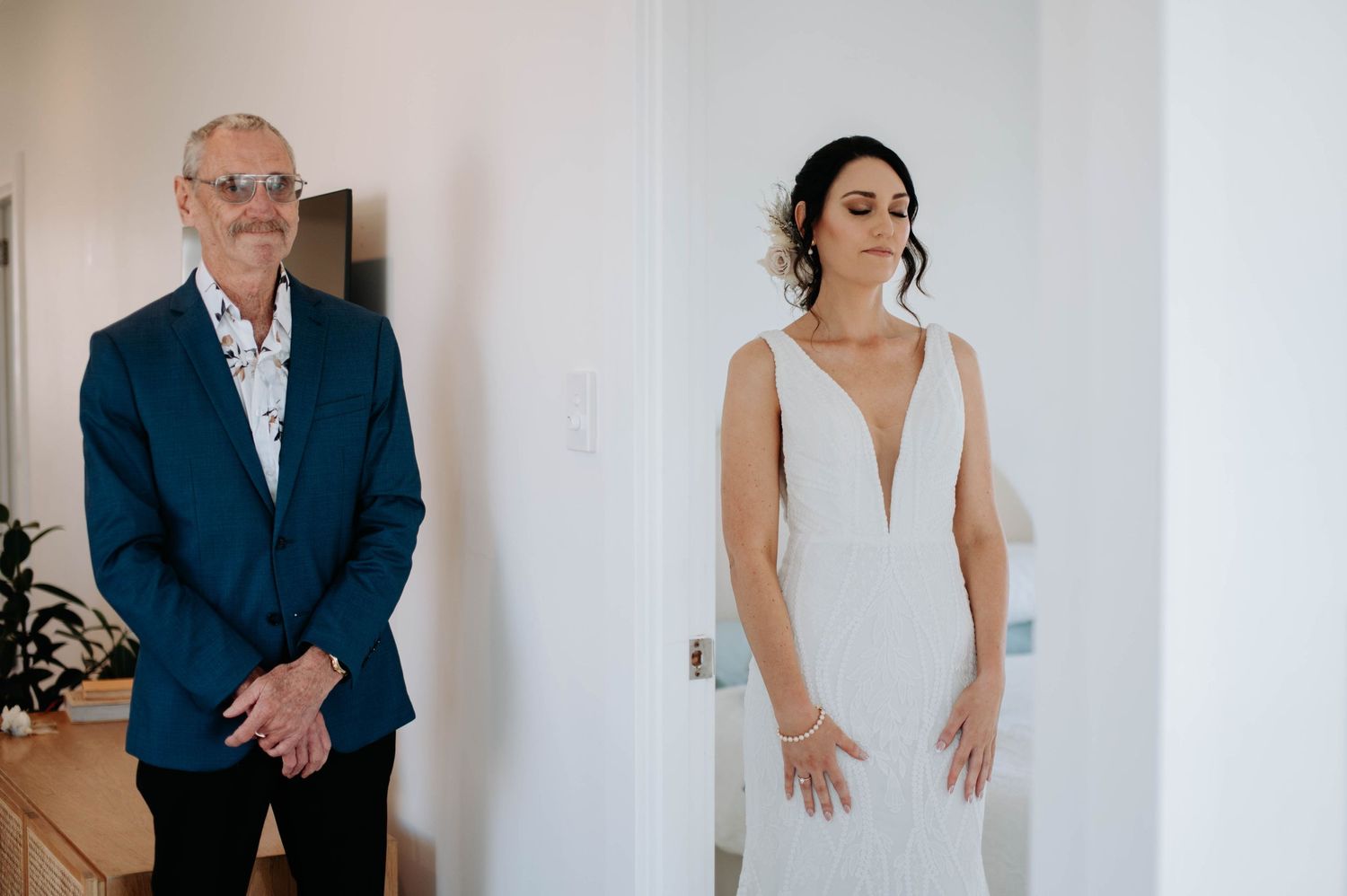 Wedding day portrait in white room showing elegant formal attire.