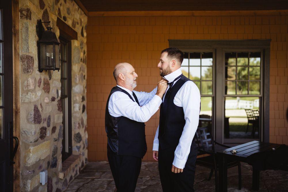 Emotional moment between two people in formal attire by stone wall.