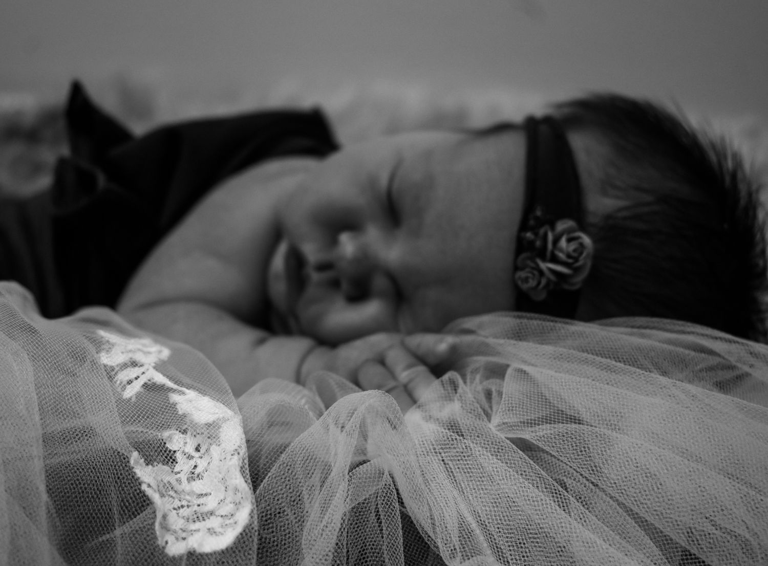 Sleeping baby in black outfit with delicate tulle fabric in black and white.