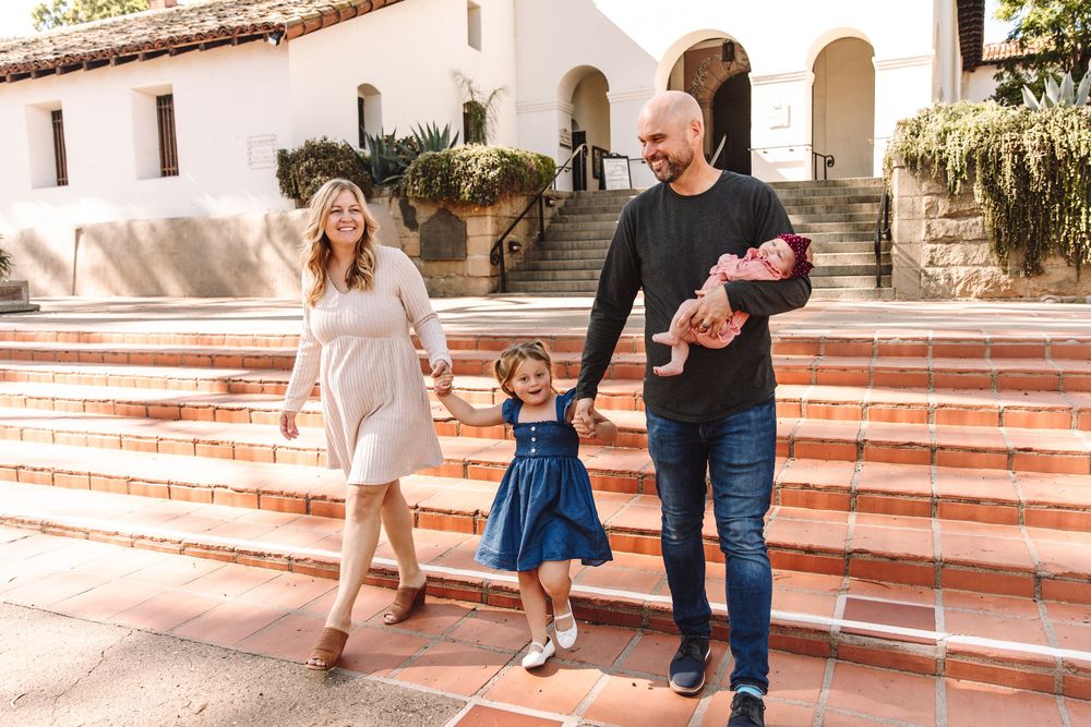 Young family walking together outside a white historic 1772 mission building.