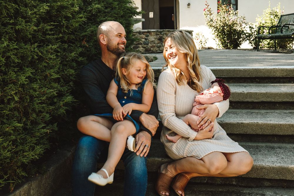 Happy family with two children sitting on outdoor steps.
