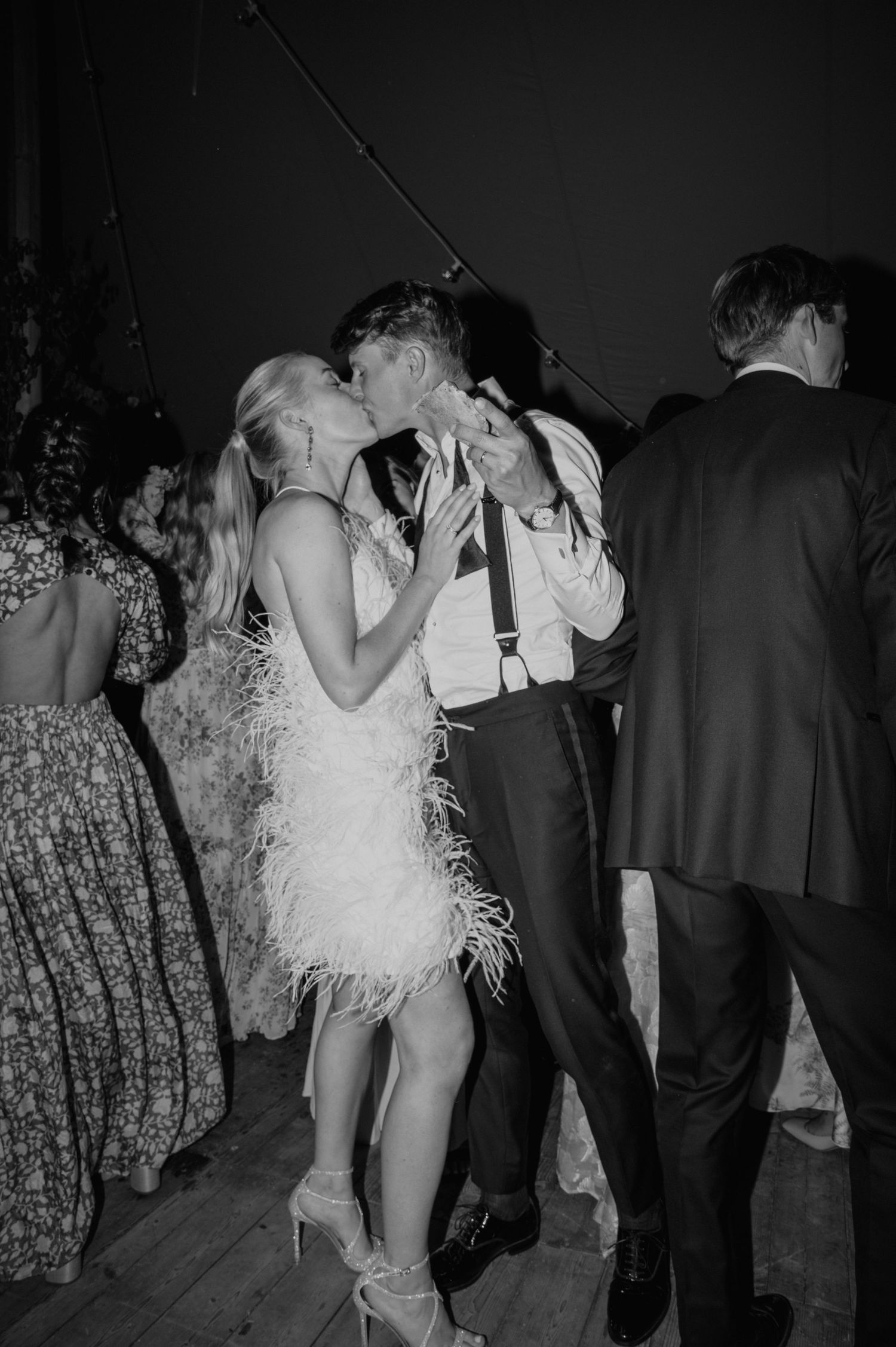 Couple dancing intimately at a wedding reception with the bride wearing a white feathered dress.