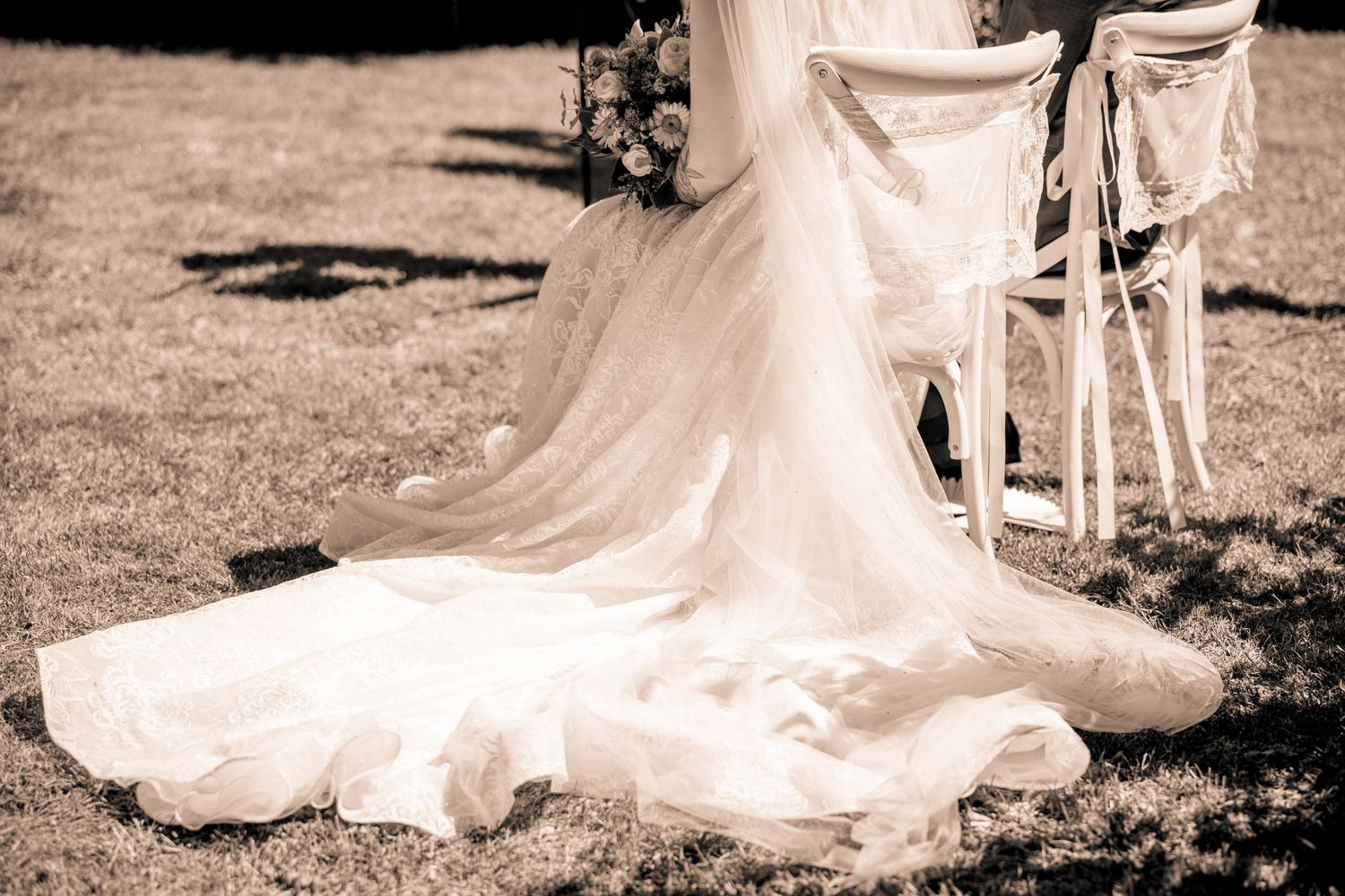 Close-up of wedding rings and hands on a white rose bouquet with baby's breath.