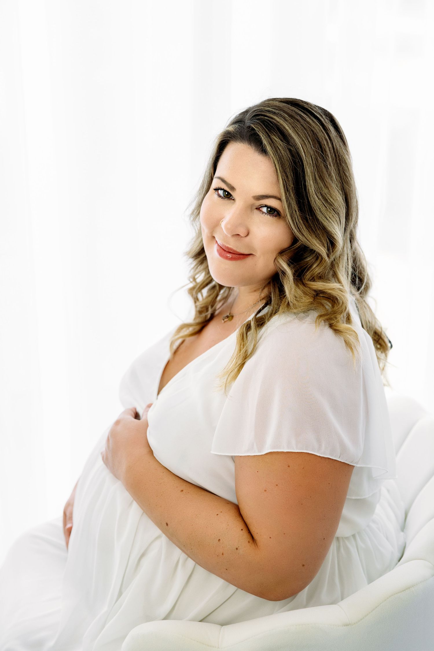 Gorgeous 36 week pregnant woman, holding belly and looking into the camera
