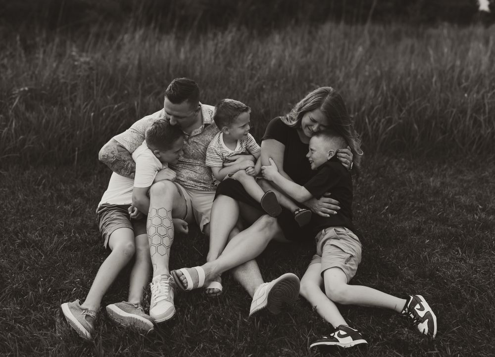 A playful black and white photo of a family lying together on grass. Colorado Springs Photographer.