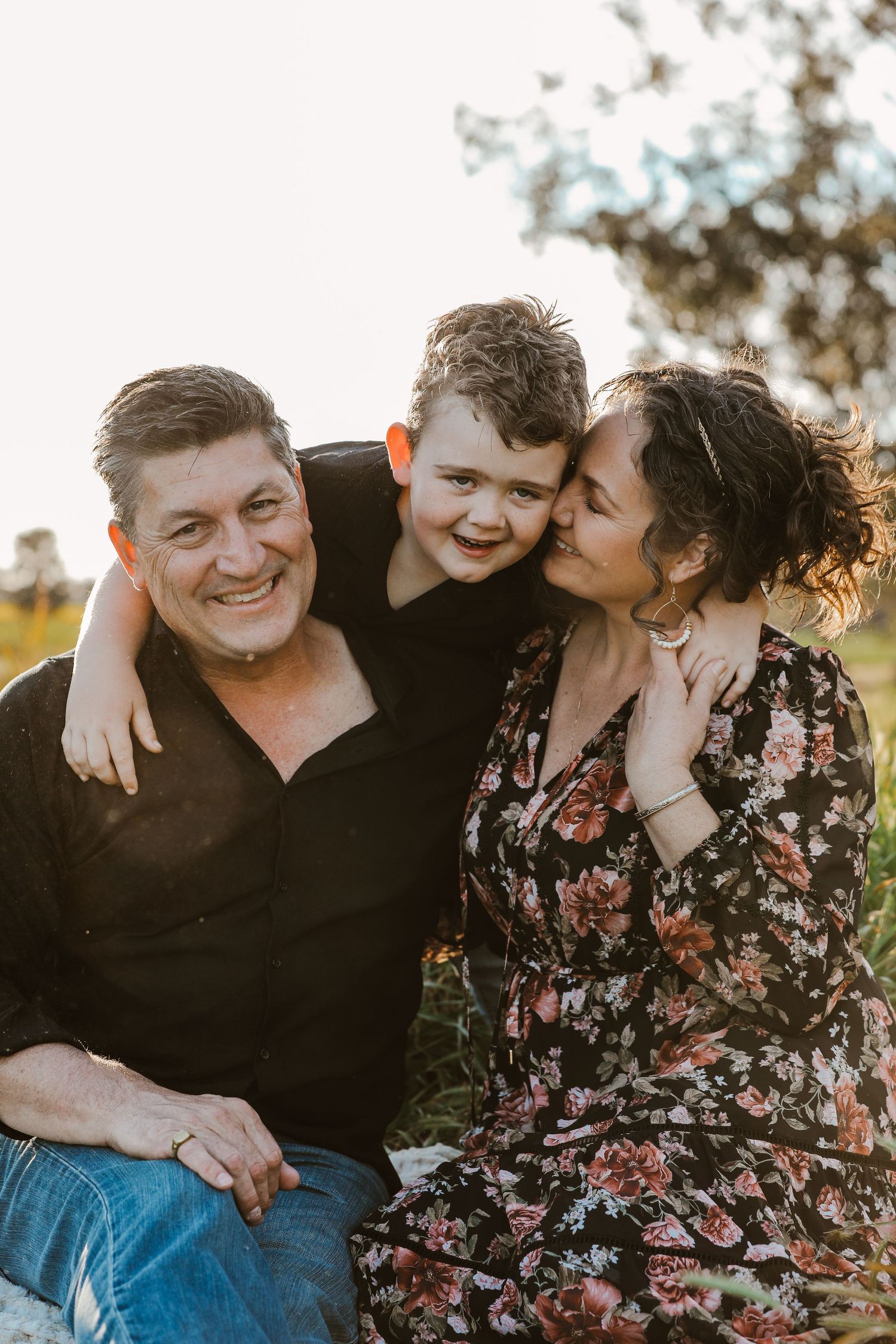 Candid family photo session showing playful moments and laughter in natural outdoor setting.