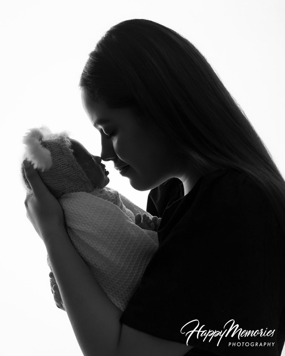 Black and white silhouette portrait of a mother gently holding her newborn baby nose to nose, by Happy Memories Photography.