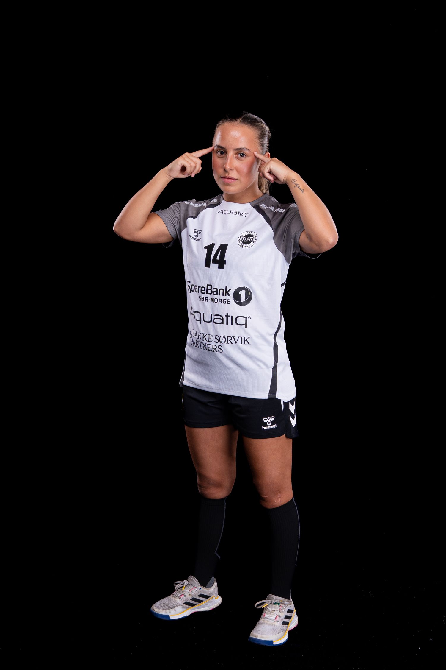 Athlete in white jersey and black shorts demonstrates dynamic leg movements against dark background.