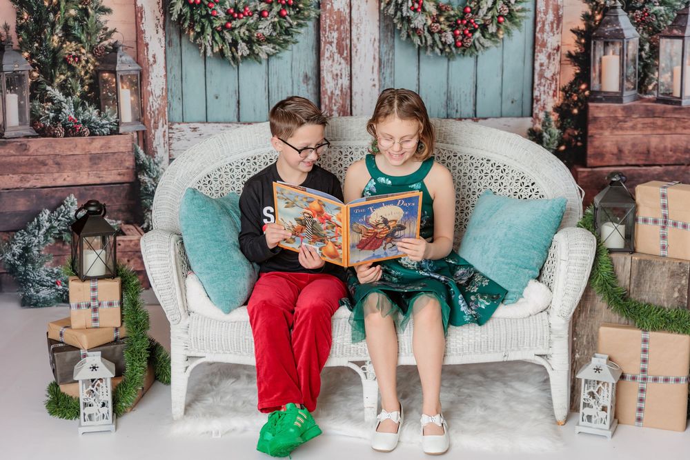 holiday scene showing kids reading books together on a cozy white wicker bench with Christmas decorations. studio session clayton nj