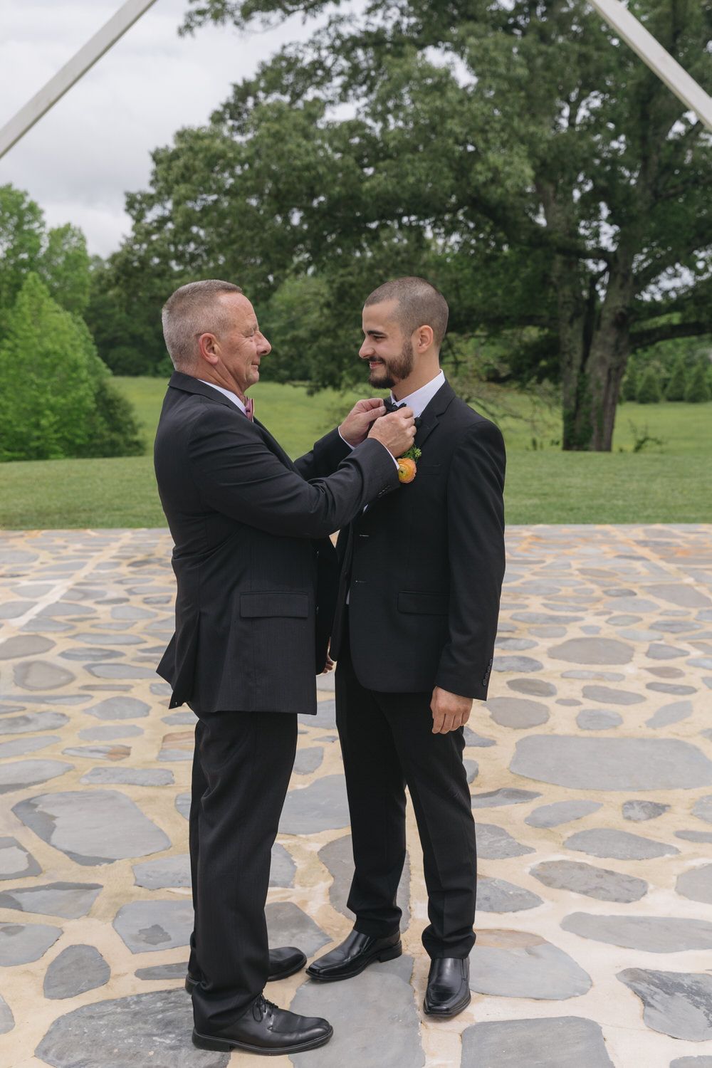 Groom's dad fixing his tie during family photos on his wedding day