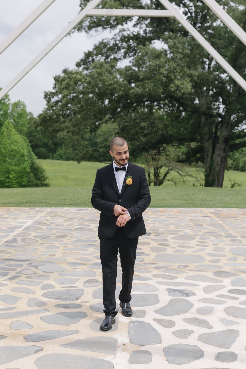 Groom walking and fixing his cuff links on his georgia wedding day