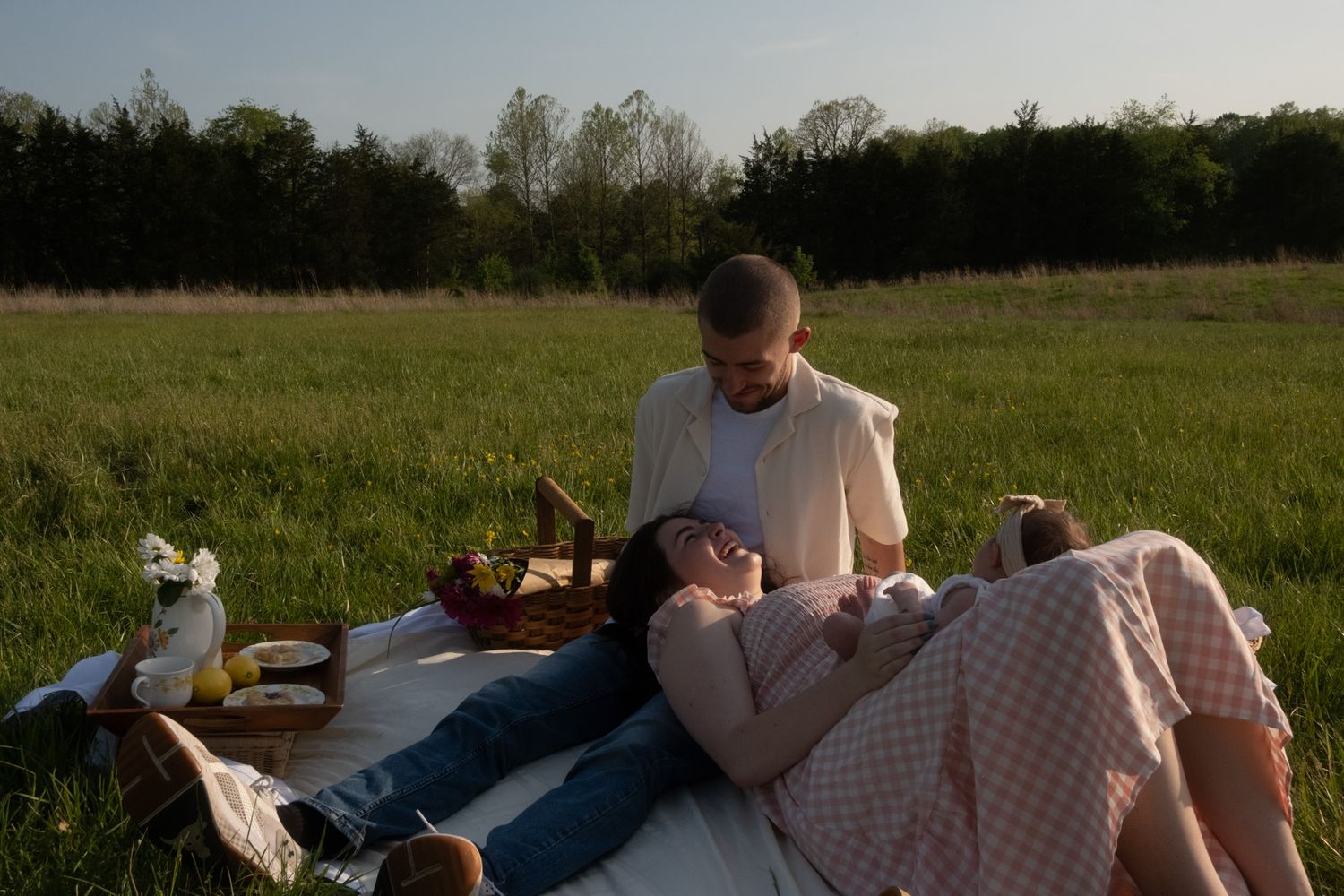 People relax together on blankets in a peaceful meadow during golden hour.