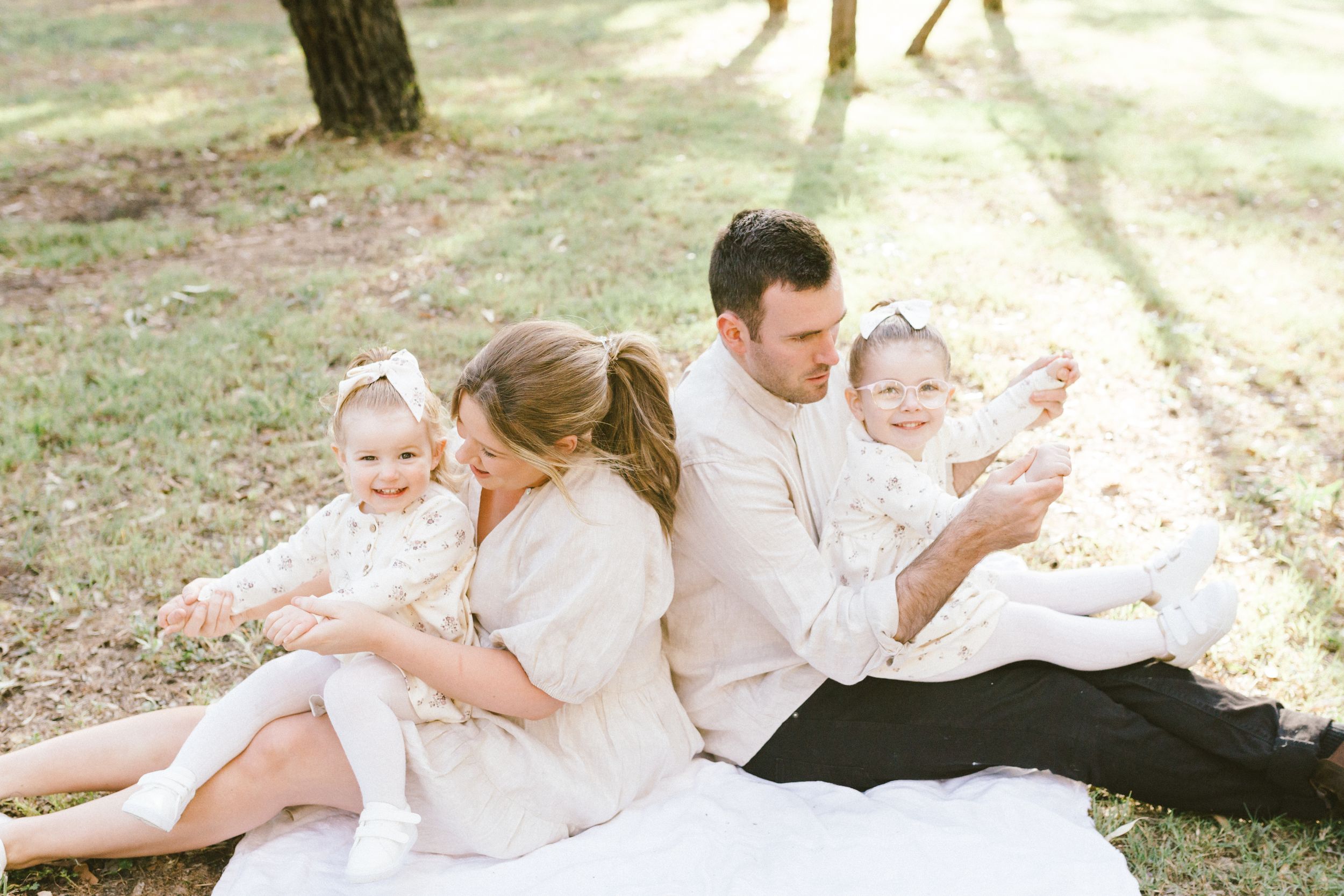 A series of connected family portraits in a park setting shows intimate moments between parents and children in soft lighting.