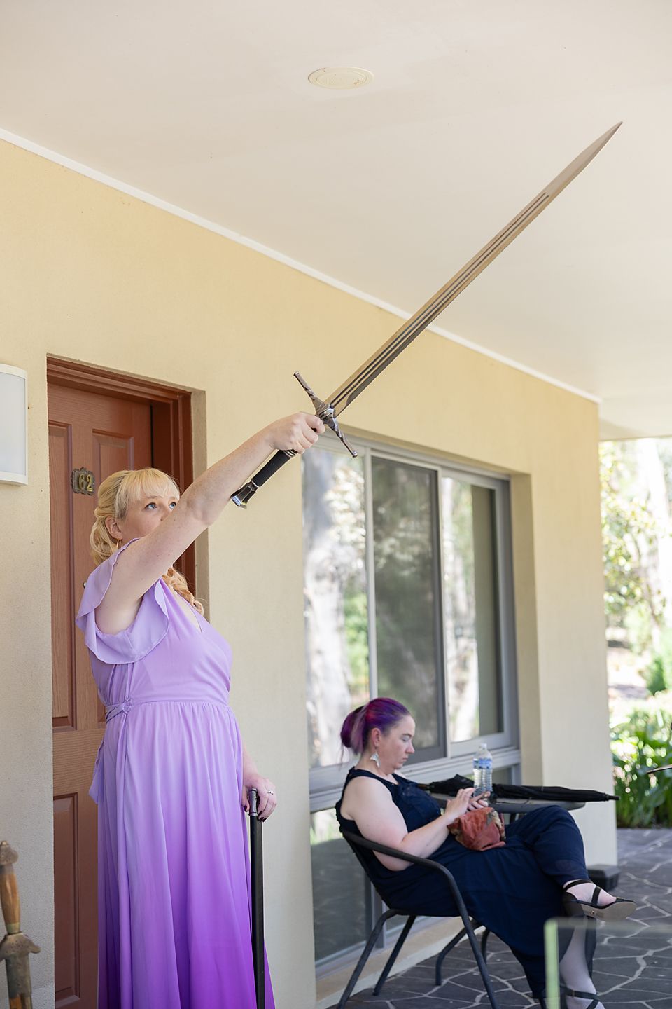 Series of photos showing a person in purple dress sitting outdoors taking photos with a sword prop at different angles.