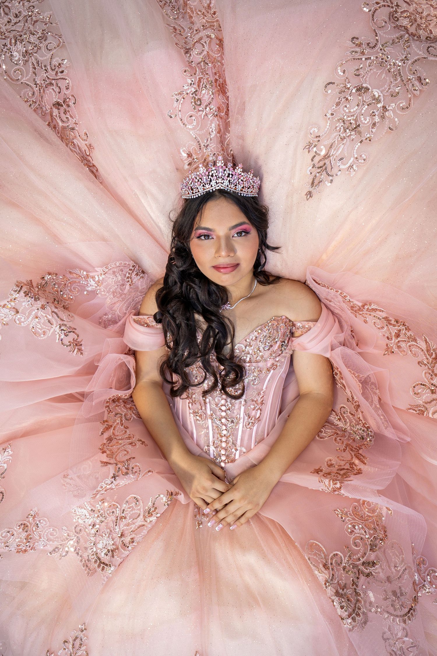 Overhead view of young woman in pink quinceañera dress with crown.