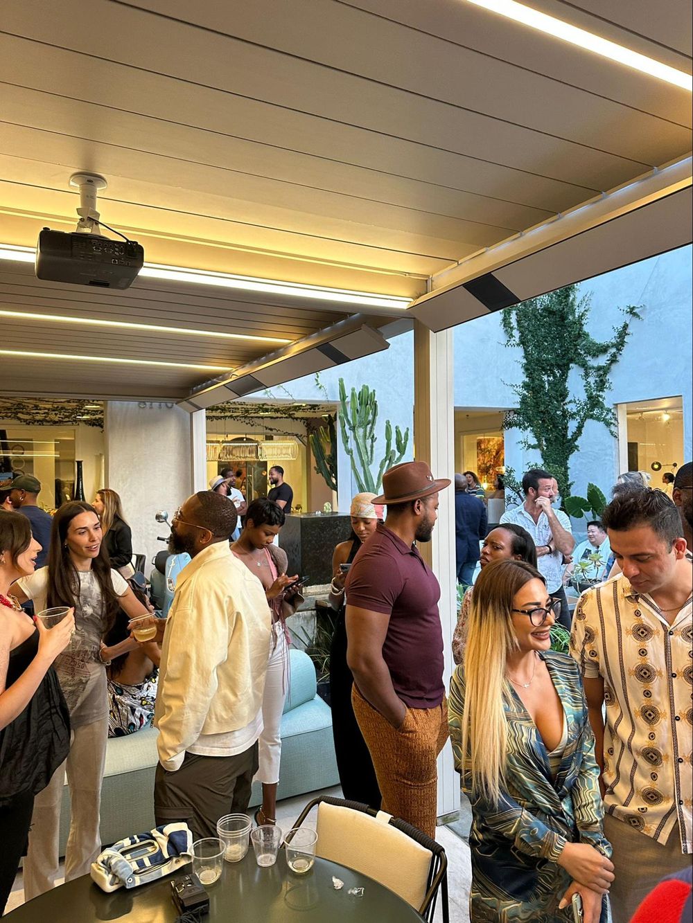 People gathered in a modern office space for a social event with bright overhead lighting and white walls.
