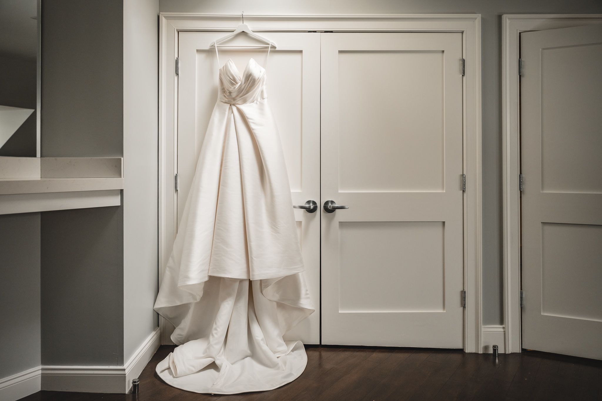 Wedding dress hanging elegantly against white paneled door.