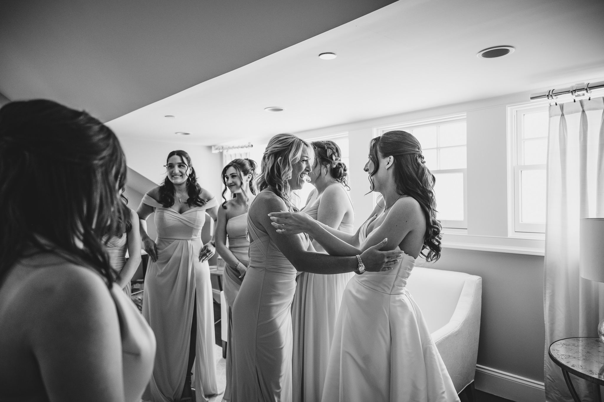 Wedding party members in formal attire gathered by window during preparations.
