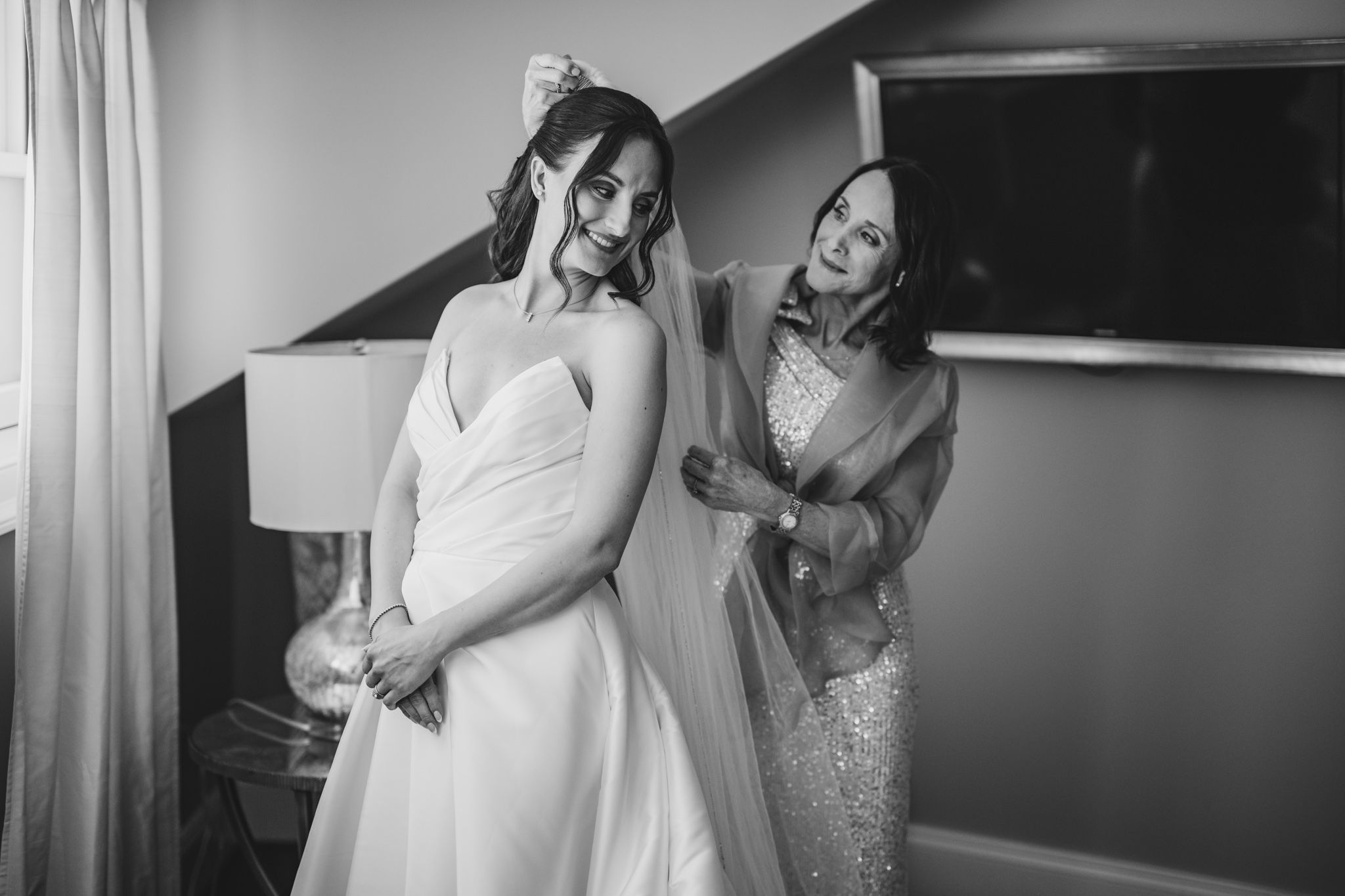 Black and white photo of wedding dress preparations in a contemporary room setting.