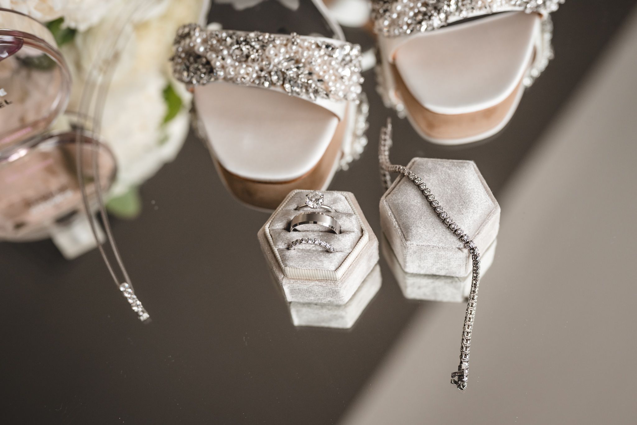 Wedding accessories including sparkly heels and jewelry arranged on table.