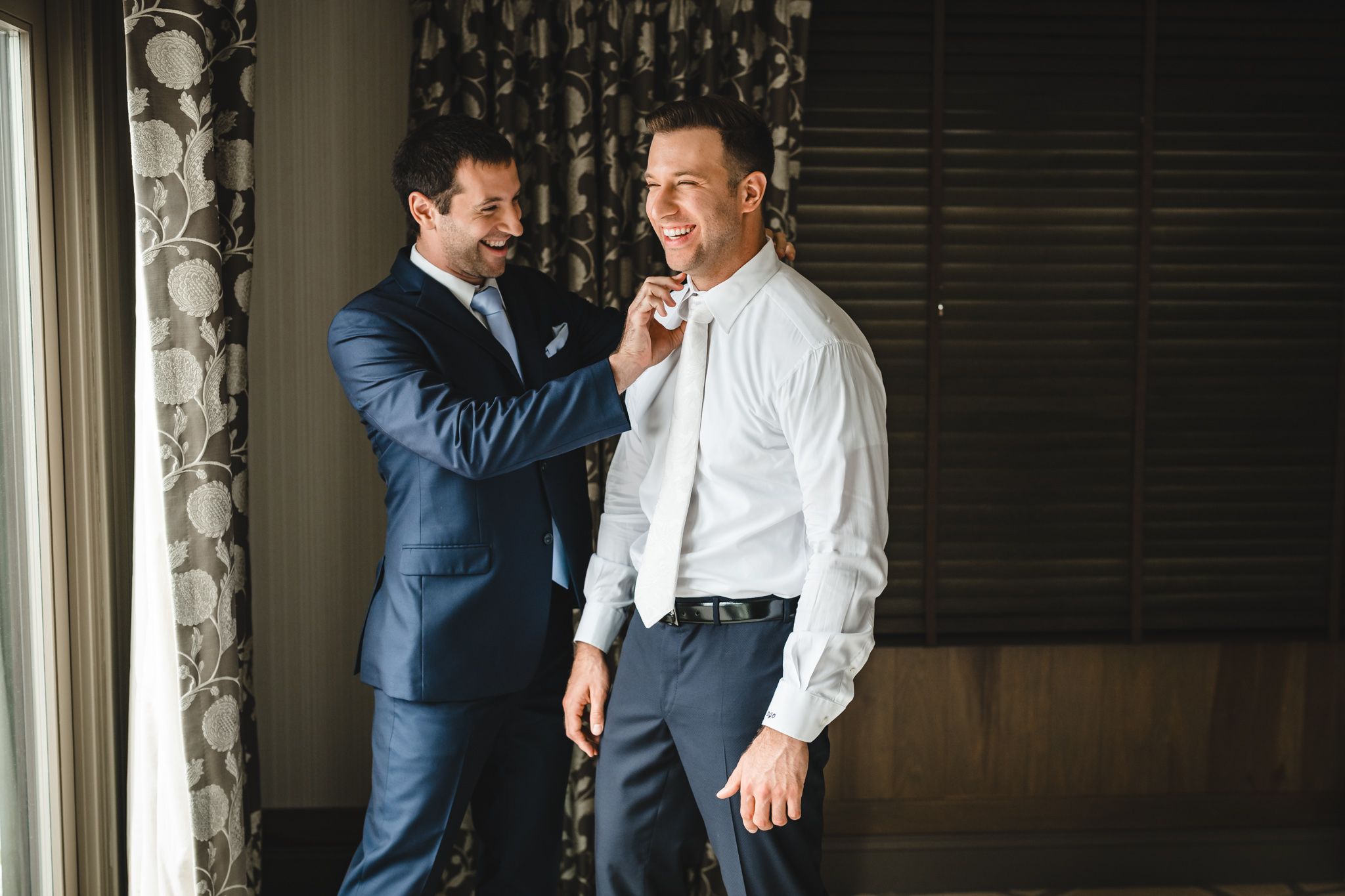 Groomsmen in navy suits and white shirts sharing a moment before the ceremony.