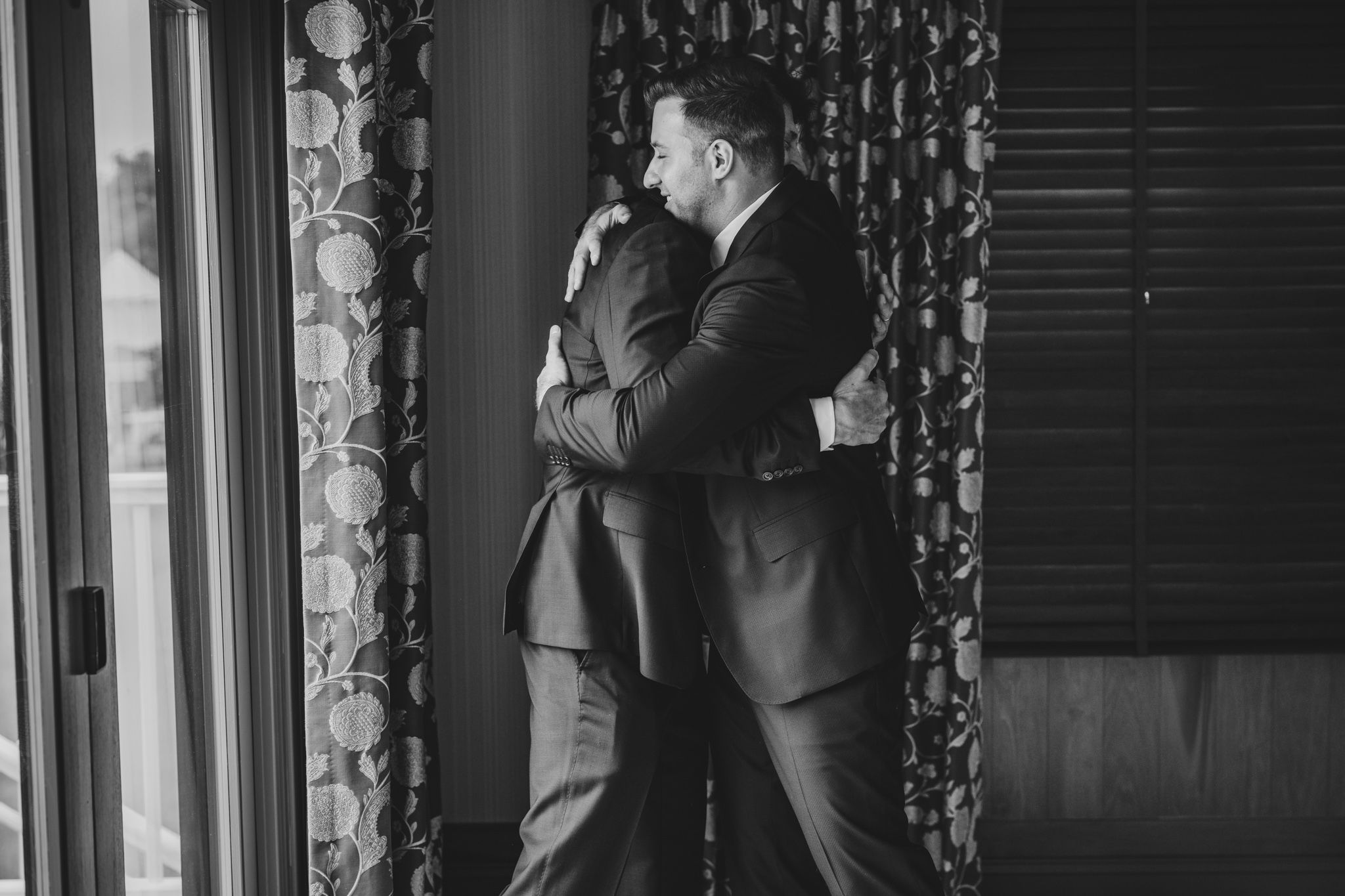 Black and white detail shots of a groom's formal attire against a patterned curtain backdrop.