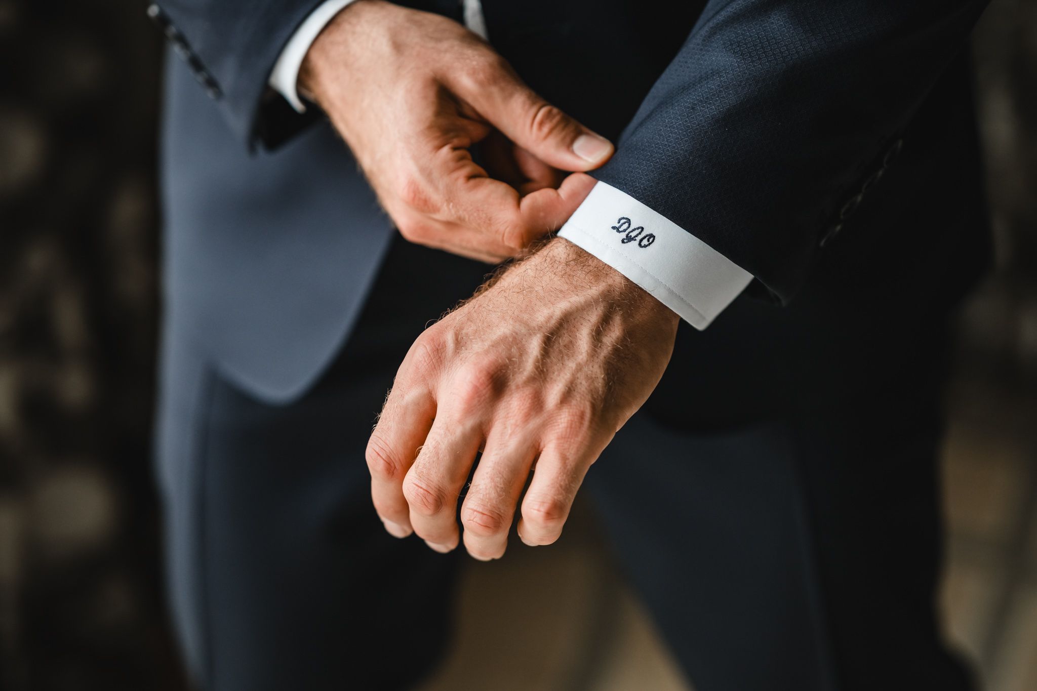 Close-up shots of hands adjusting suit cuffs and details of formal wedding attire.