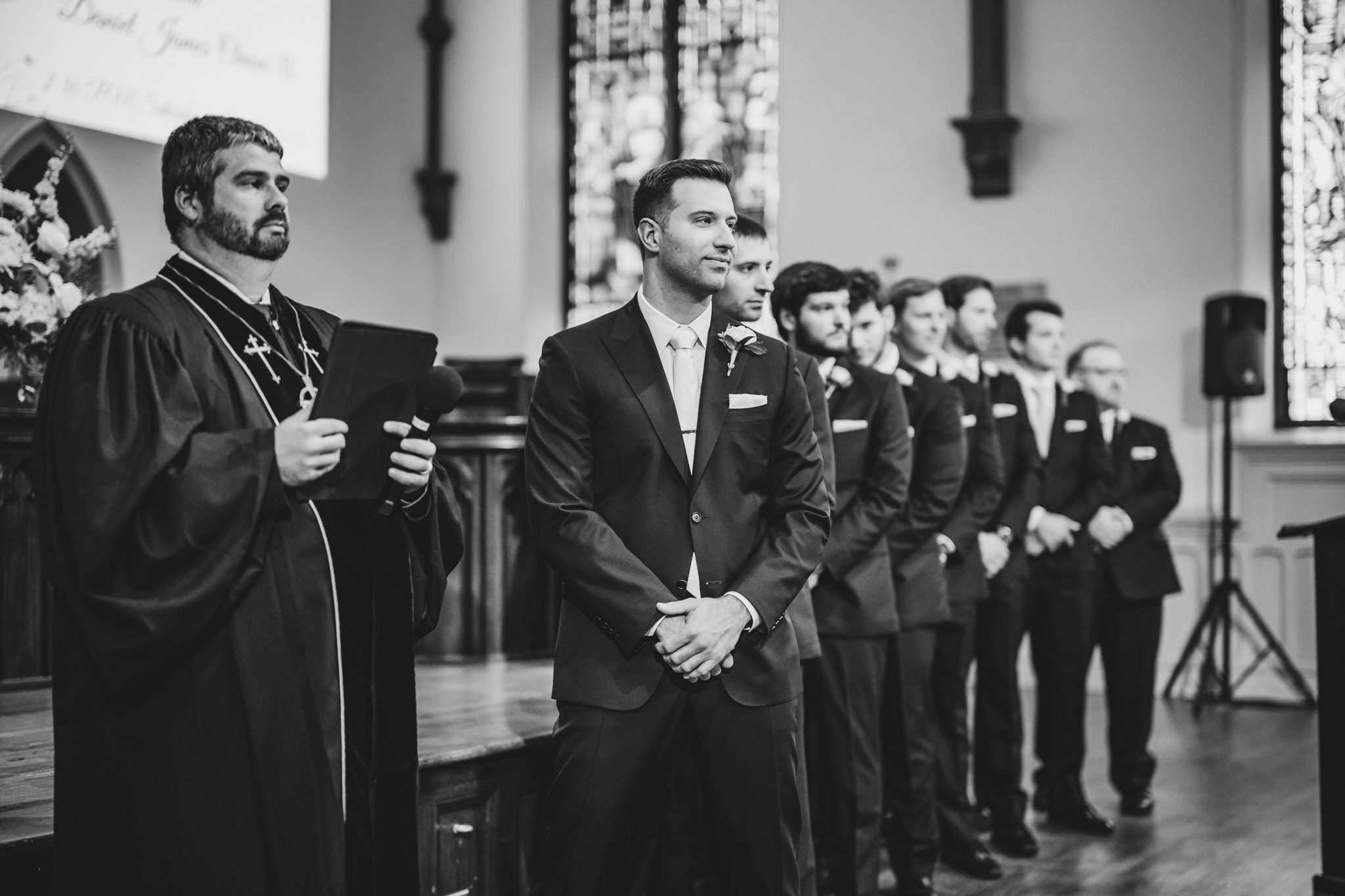 Formal black and white portrait of wedding party lined up in matching attire.