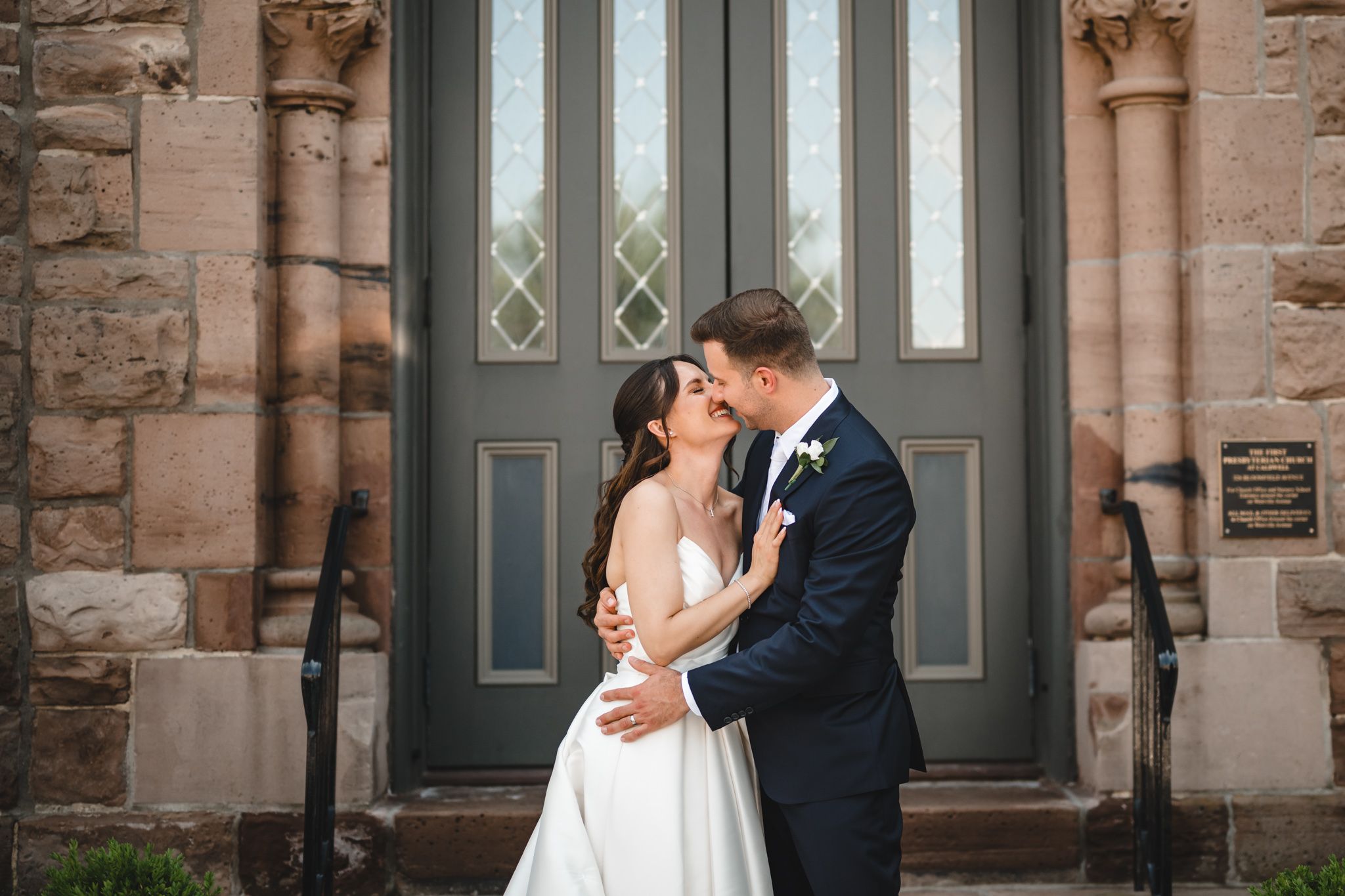 Romantic wedding portrait against rustic stone church exterior.