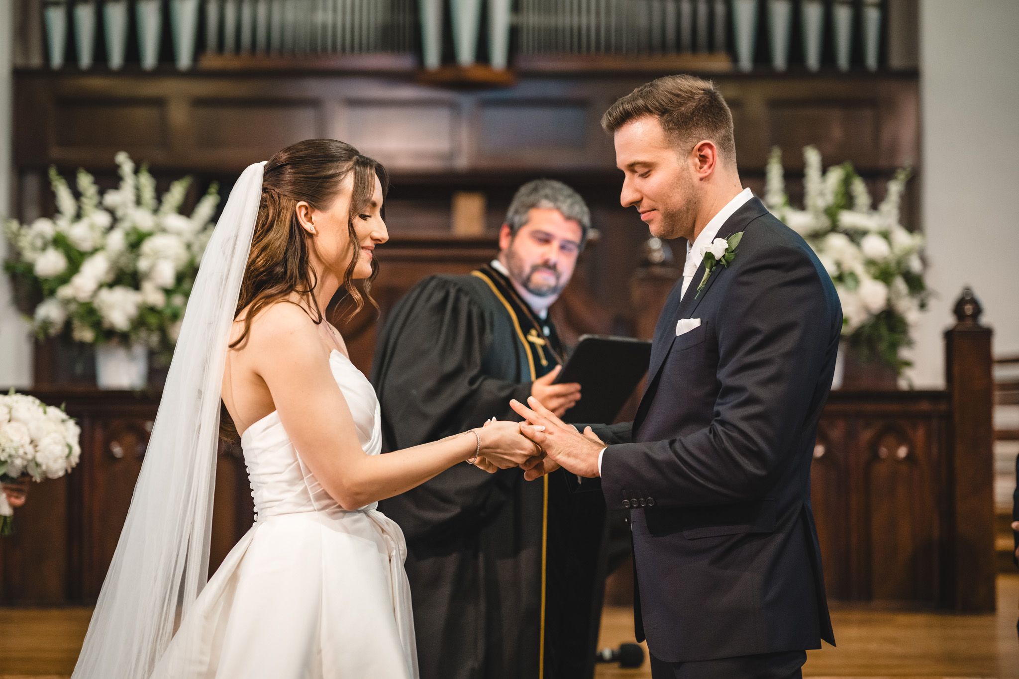 Wedding ceremony in progress with elegant floral arrangements and church organ pipes.