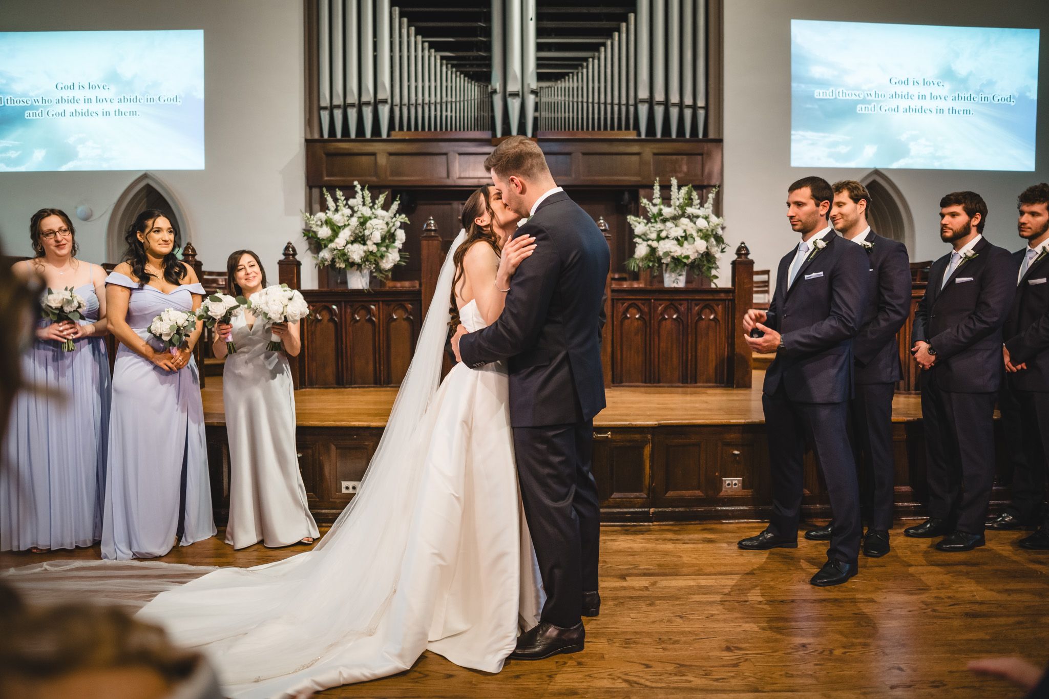 Church wedding ceremony with projection screens and organ pipes visible in the background.