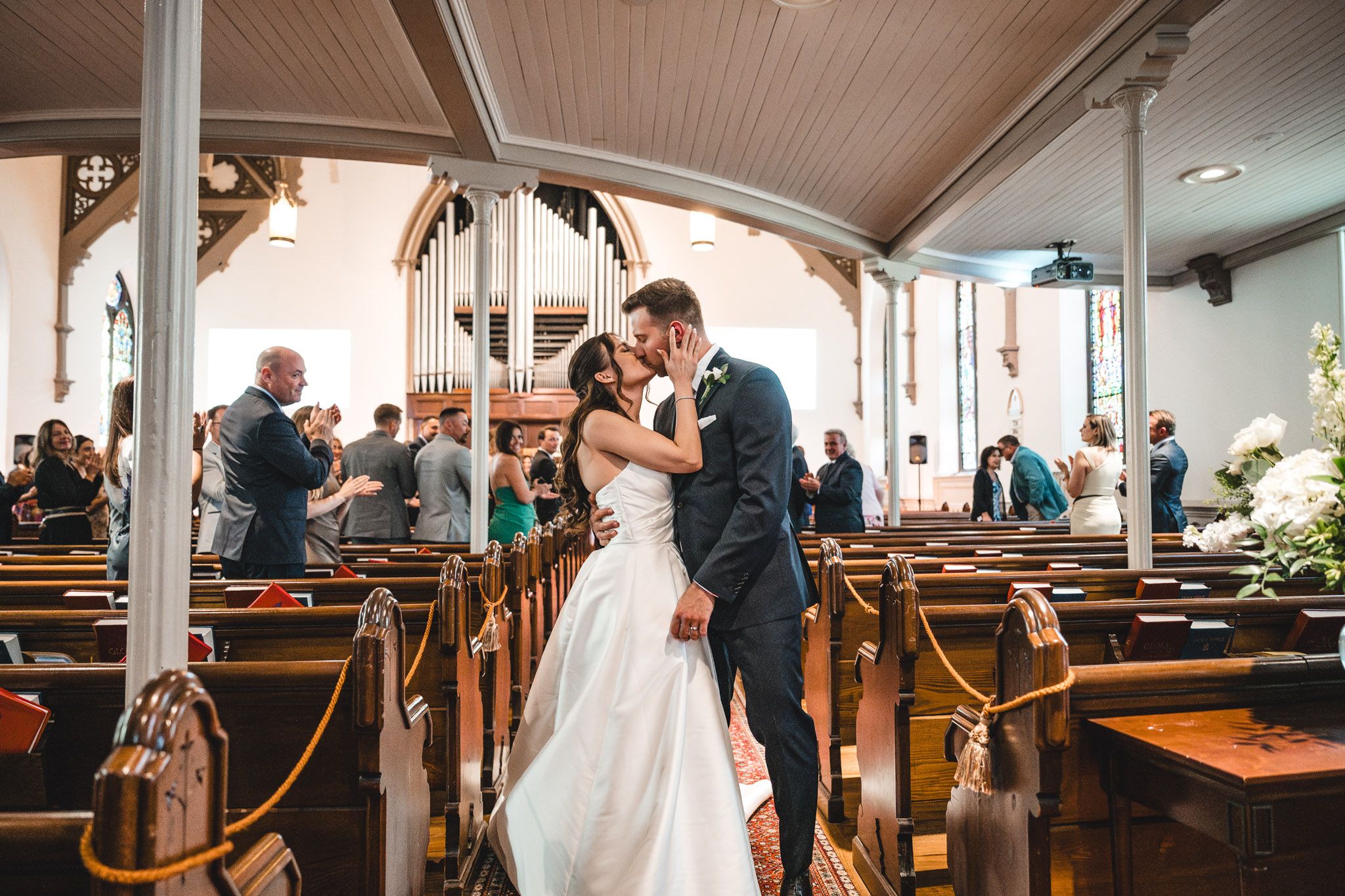 Wide angle view of a church wedding ceremony with wooden pews and architectural details.
