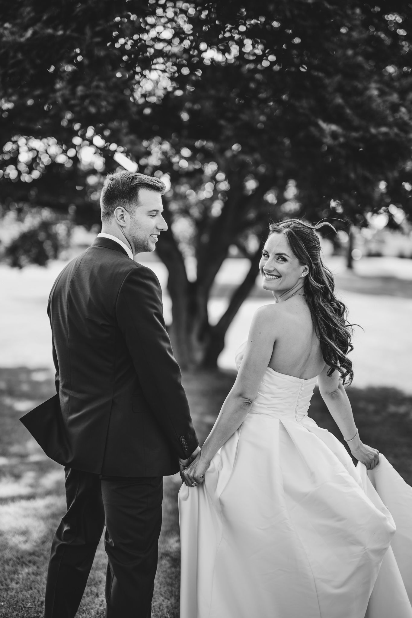 Candid black and white wedding photos capture playful moments between the couple.