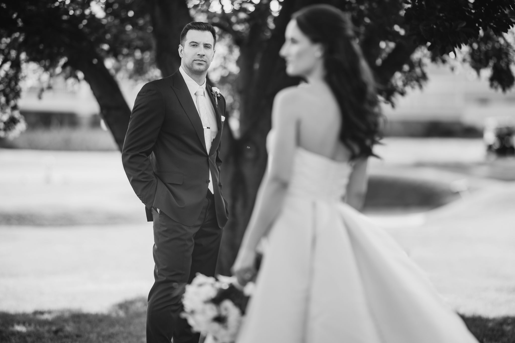 A romantic wedding couple embraces during their outdoor photo session in natural lighting.
