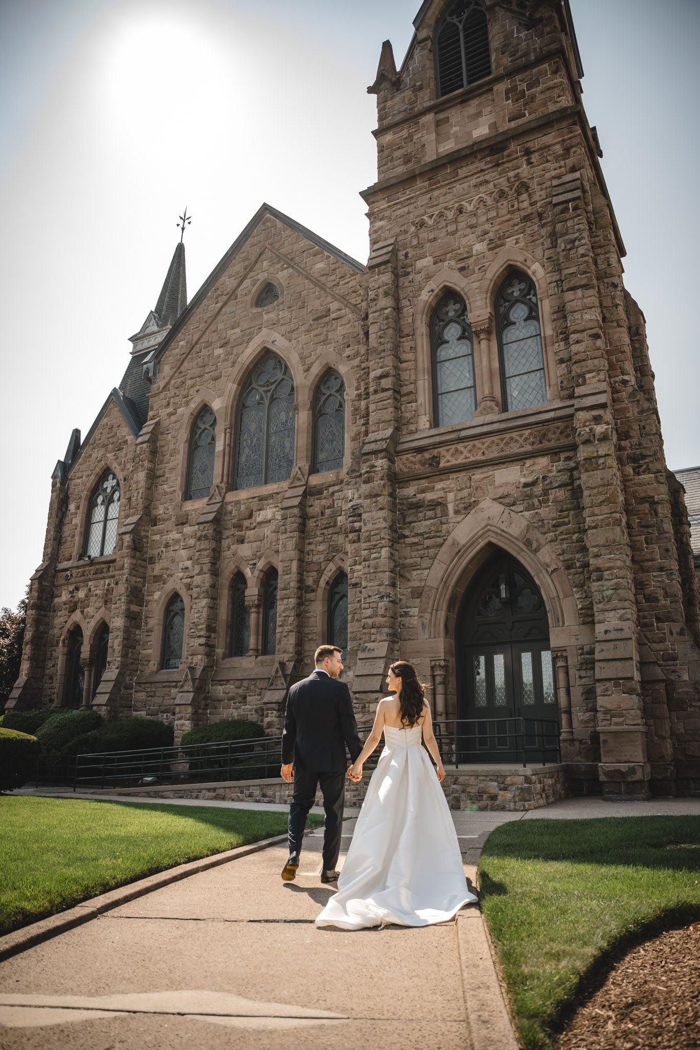 Gothic stone church exterior with arched windows and doorways provides a dramatic backdrop for wedding photos.