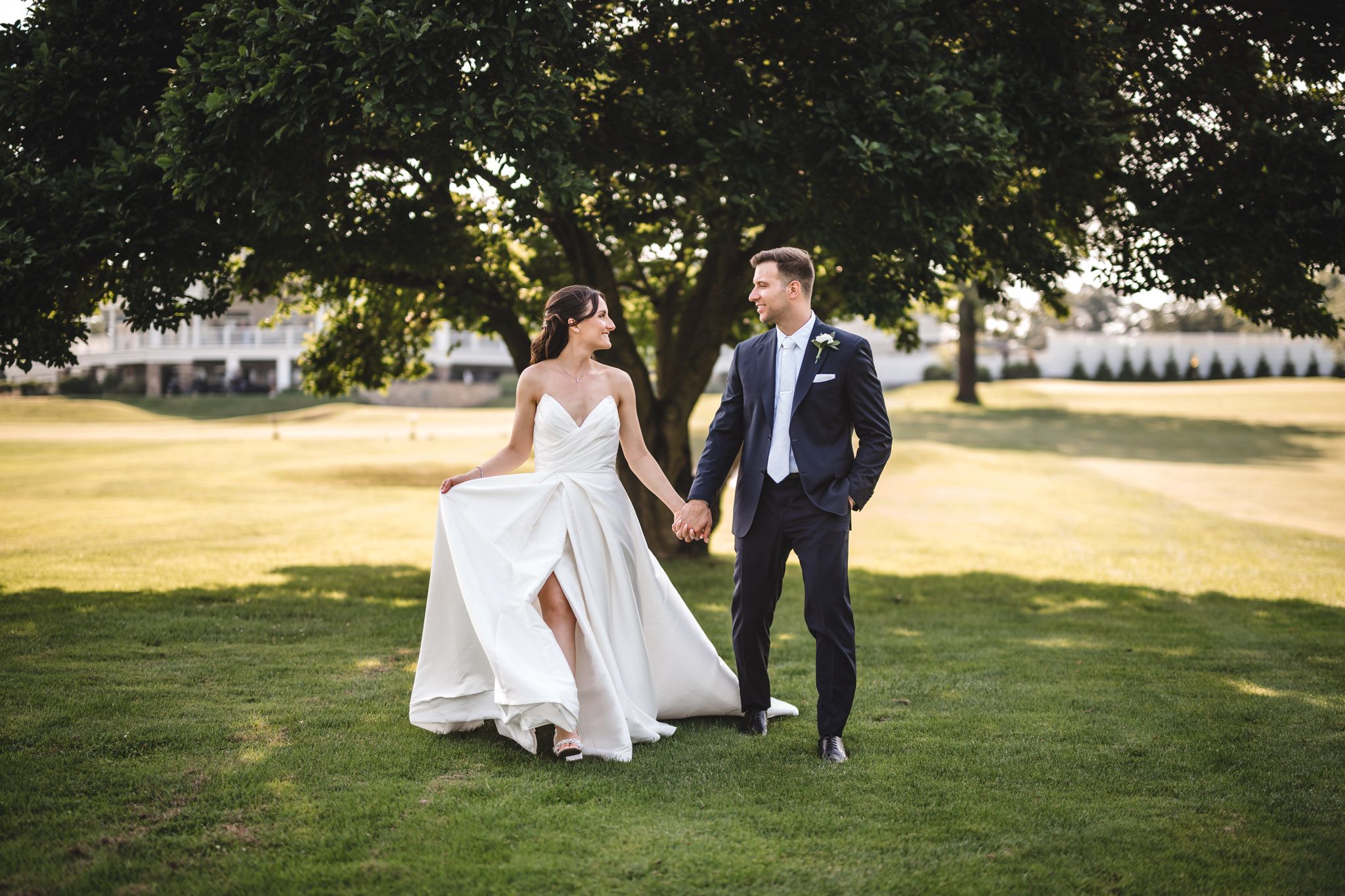 Newlyweds share romantic moments on a sun-drenched lawn during golden hour.