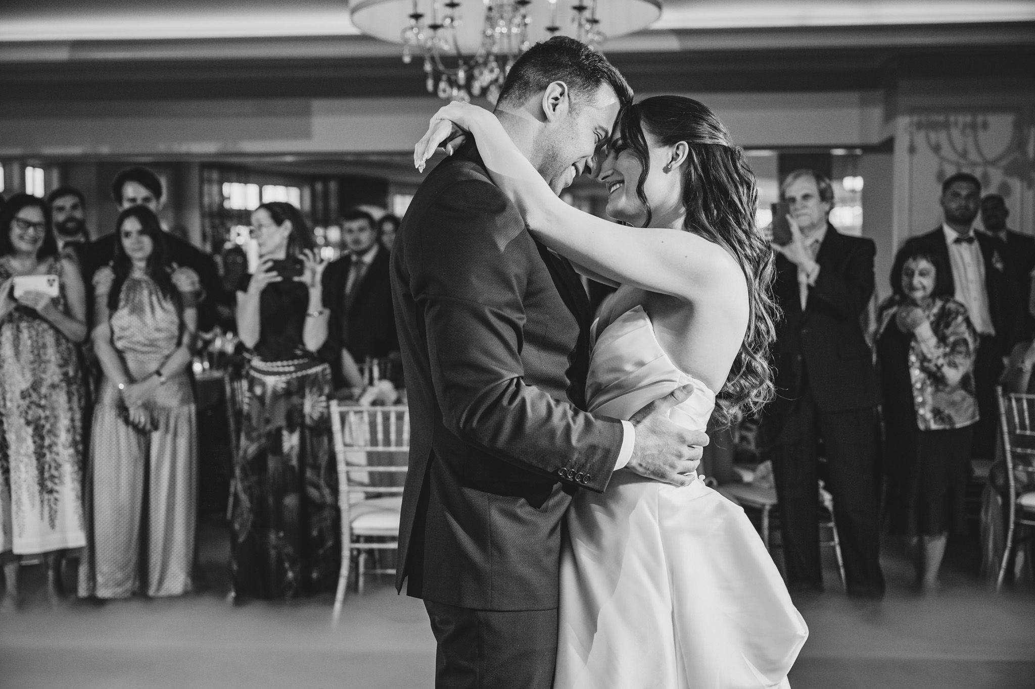 Black and white photo of romantic dance performance with guests watching from the sidelines.