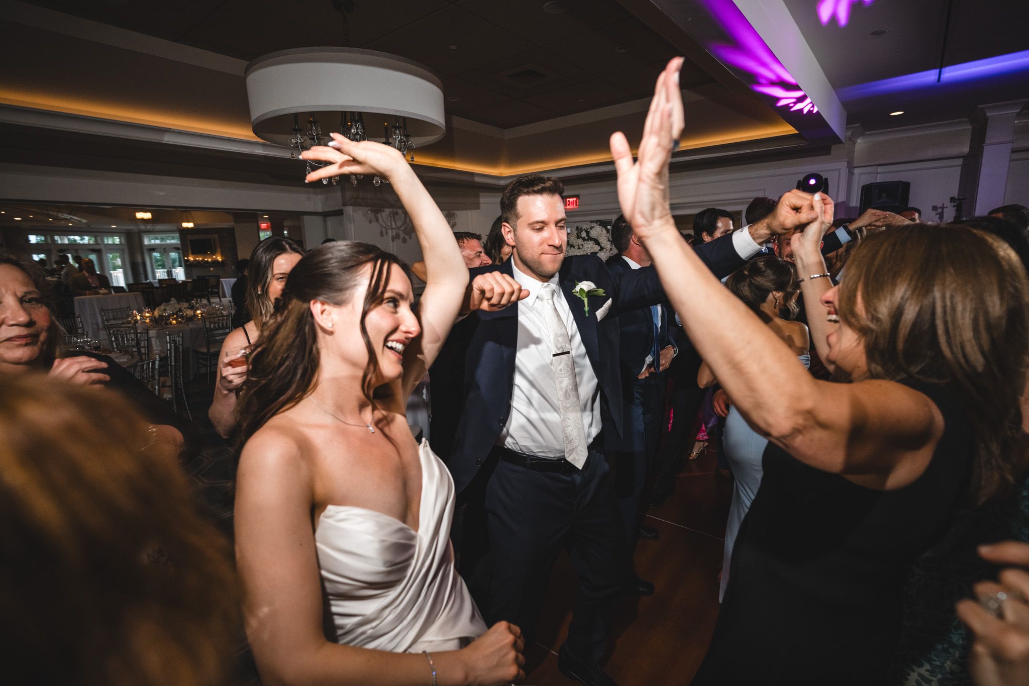 Nightclub atmosphere with purple lighting as party guests dance and celebrate.
