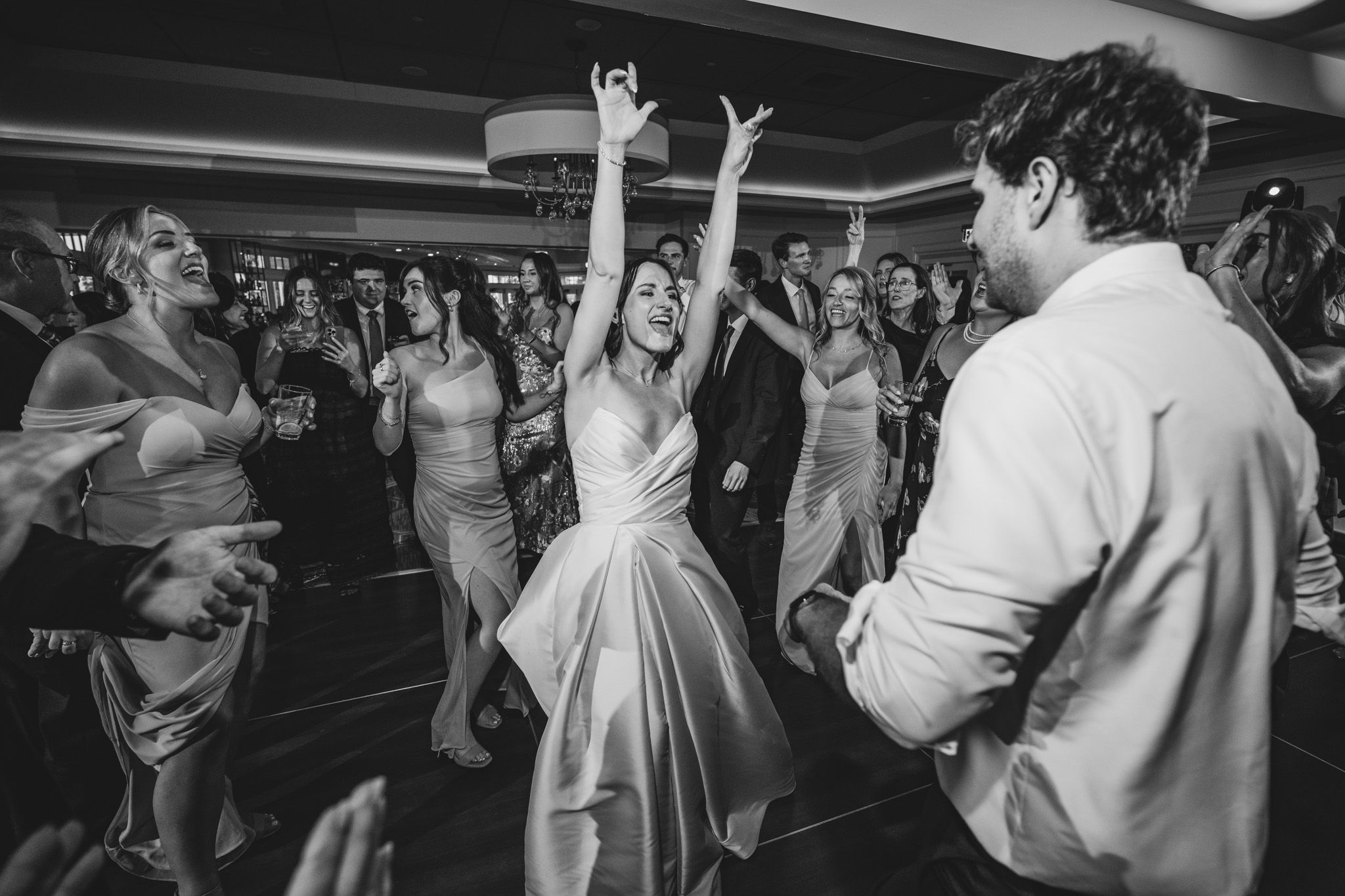 Wedding reception guests dancing and celebrating energetically on a crowded dance floor.