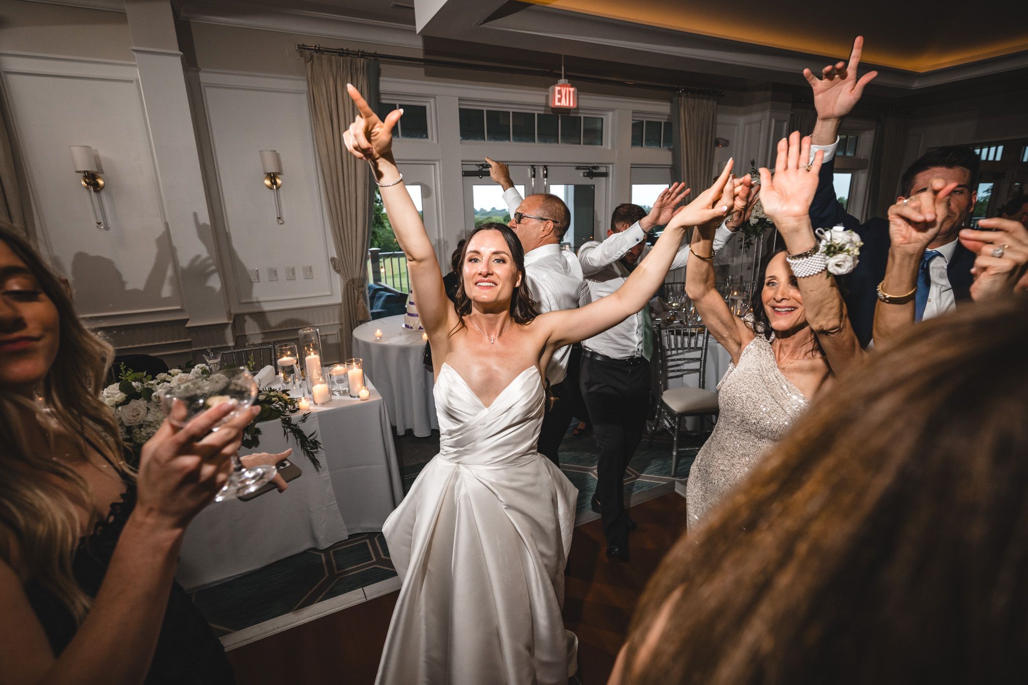 Celebration on a dance floor with guests raising their arms and dancing under ambient lighting.