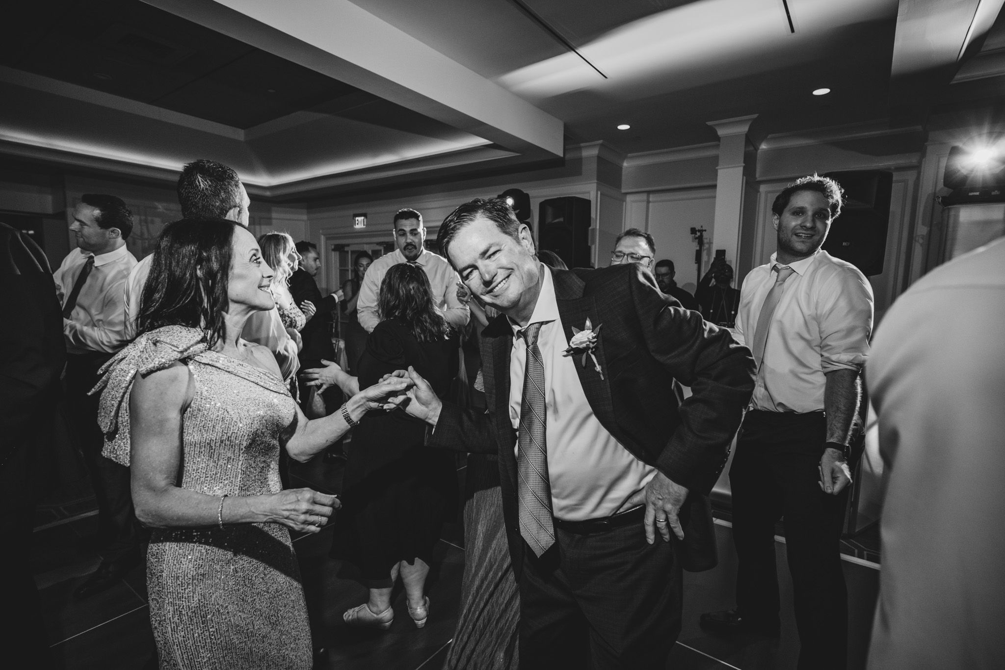 Candid moments of wedding guests dancing and mingling at an indoor reception.
