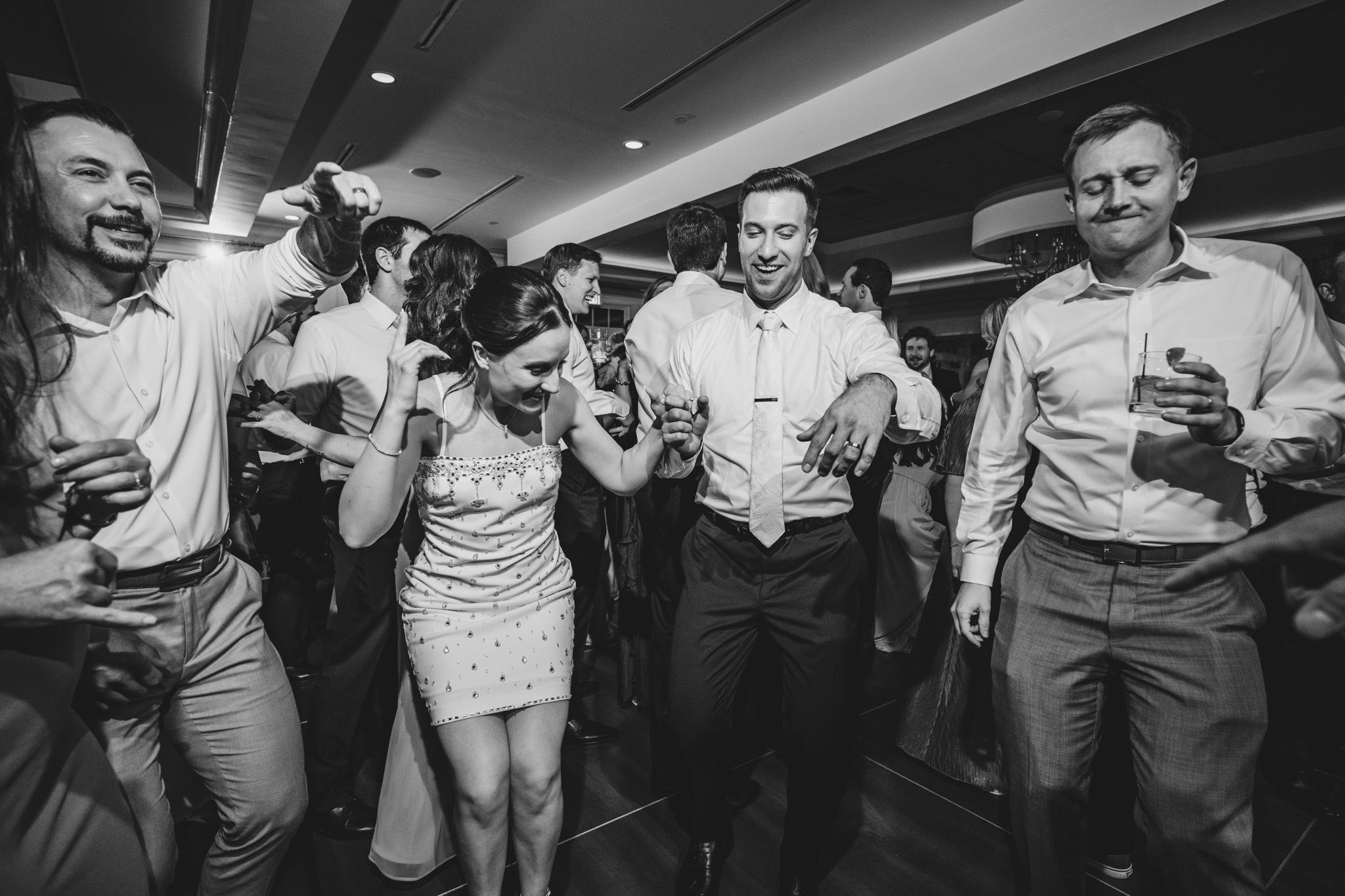 Wedding reception guests dancing and laughing during an energetic celebration.