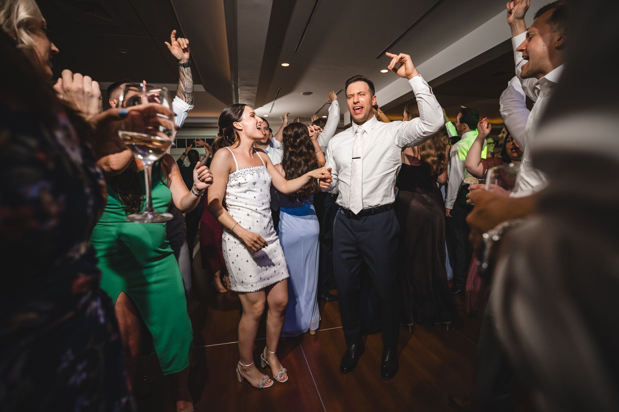 Wedding celebration with guests dancing and having fun on a dark dance floor.