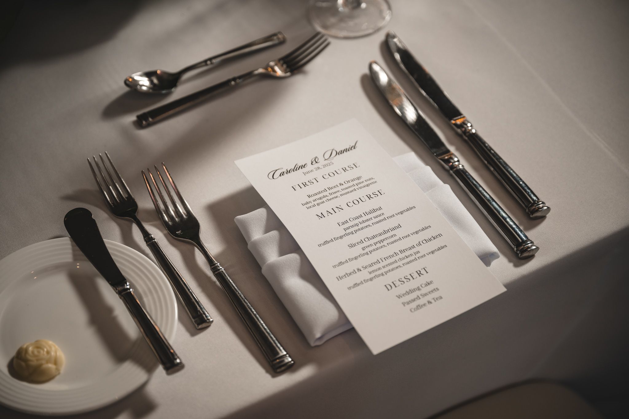 Formal place settings with silverware and menu cards at a wedding reception.