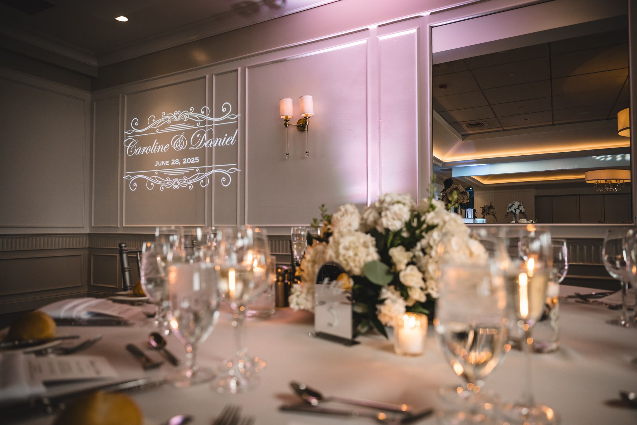 Romantic candlelit wedding reception table with white floral centerpieces.