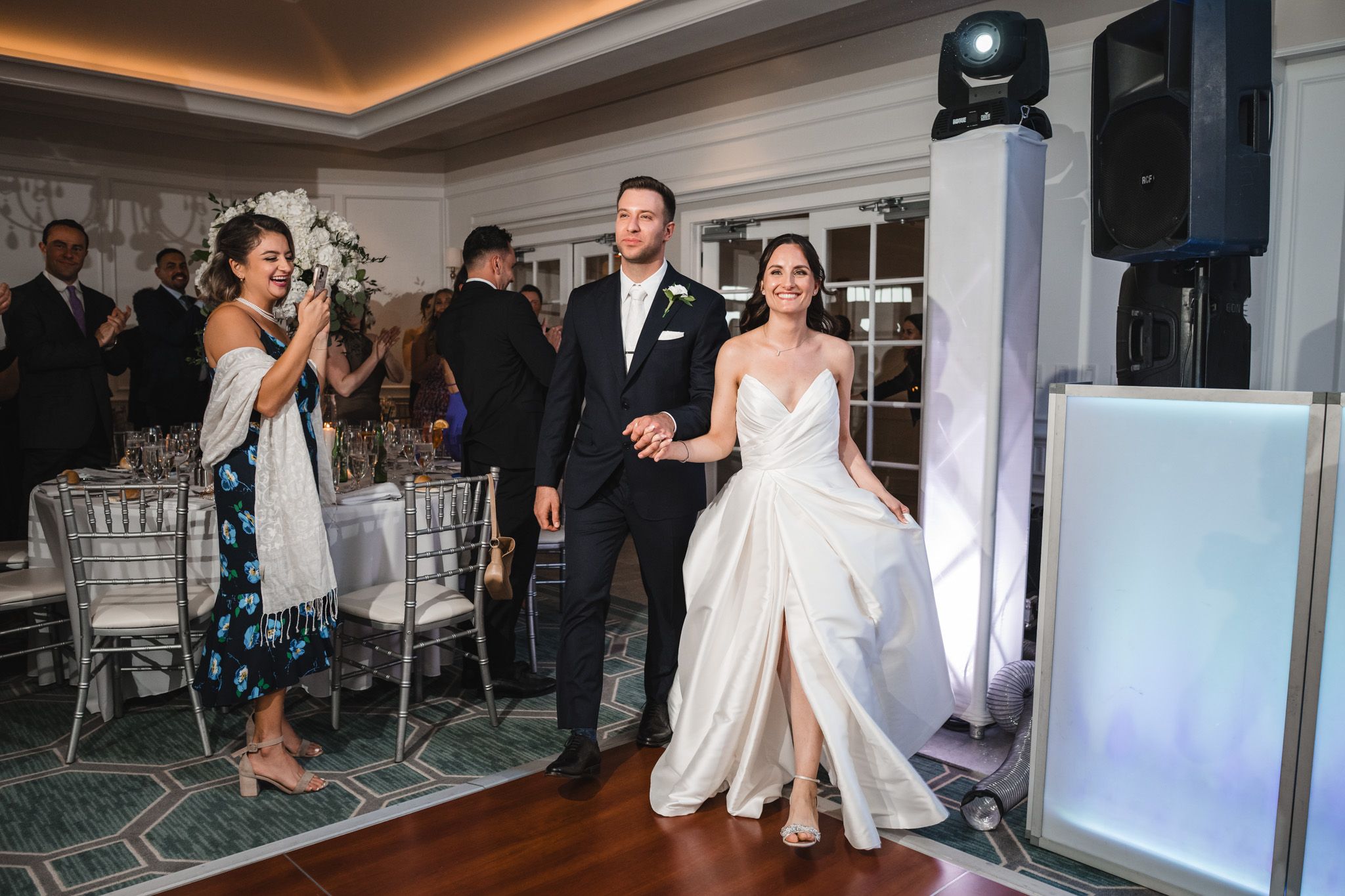 Couple performs first dance in elegant ballroom with dramatic lighting and fog effects.
