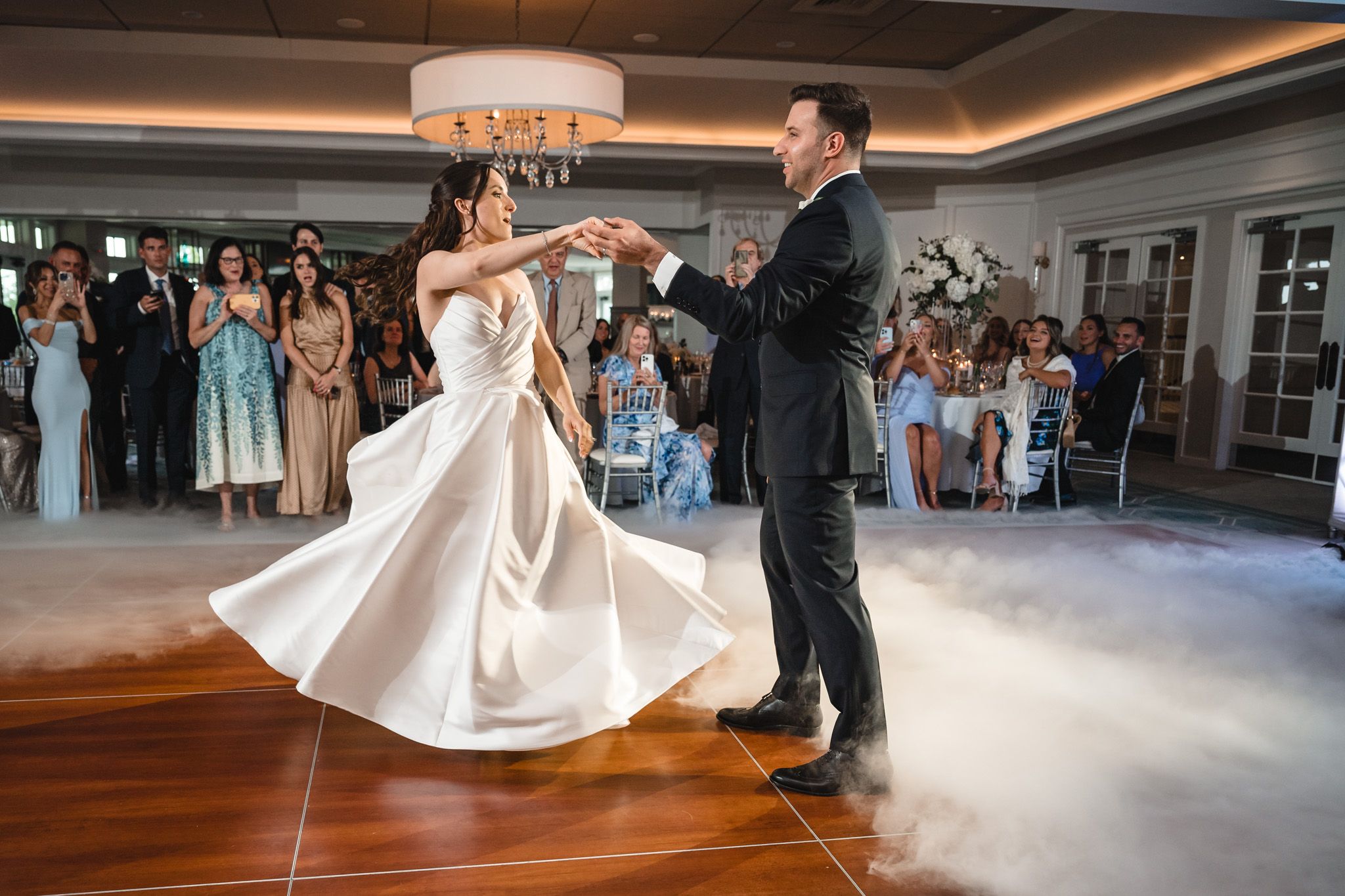 Elegant wedding dance with fog machine effects creating dreamy atmosphere on ballroom floor.