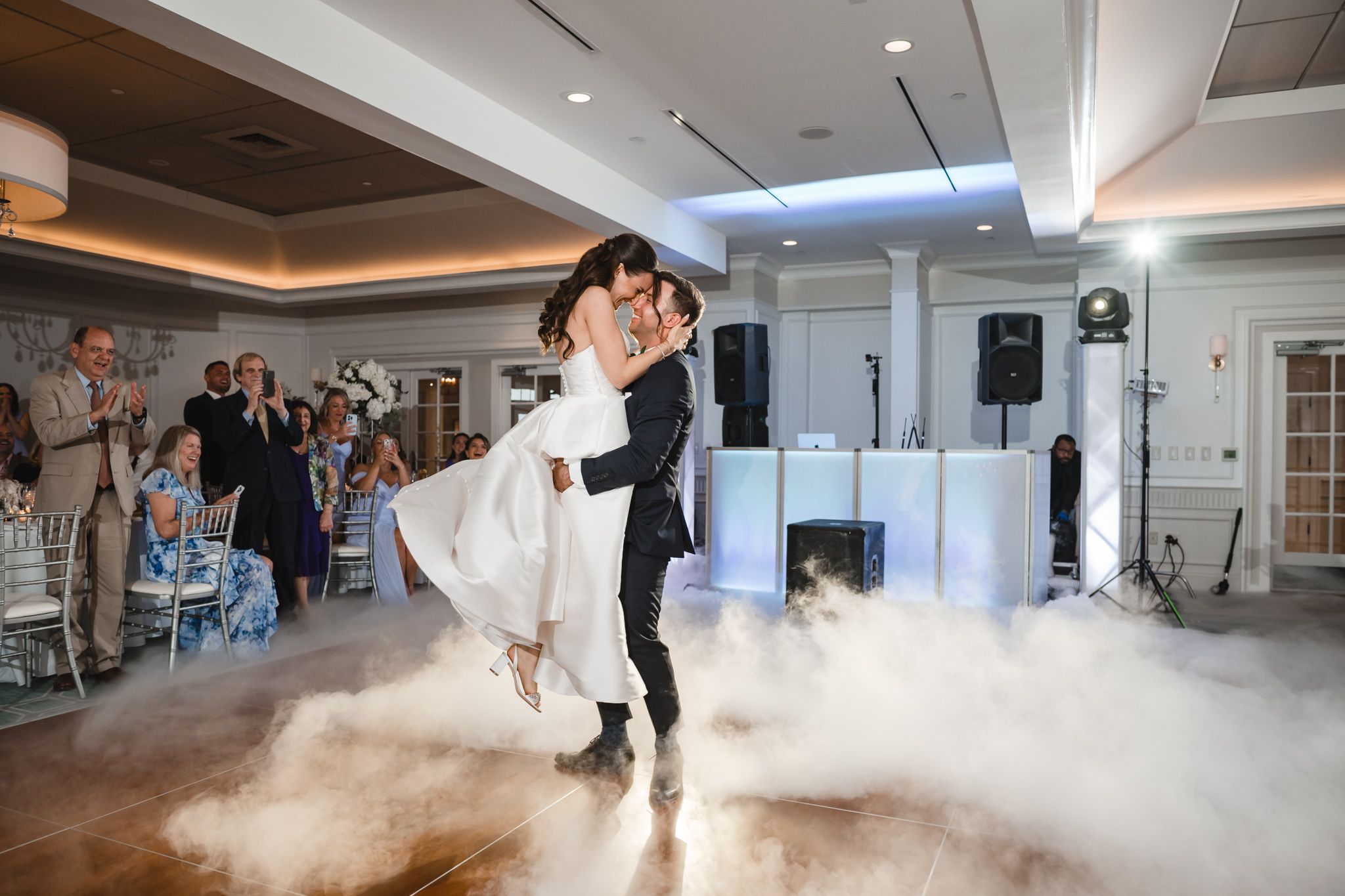 Low-angle view of wedding dance performance with atmospheric fog effects in spacious venue.