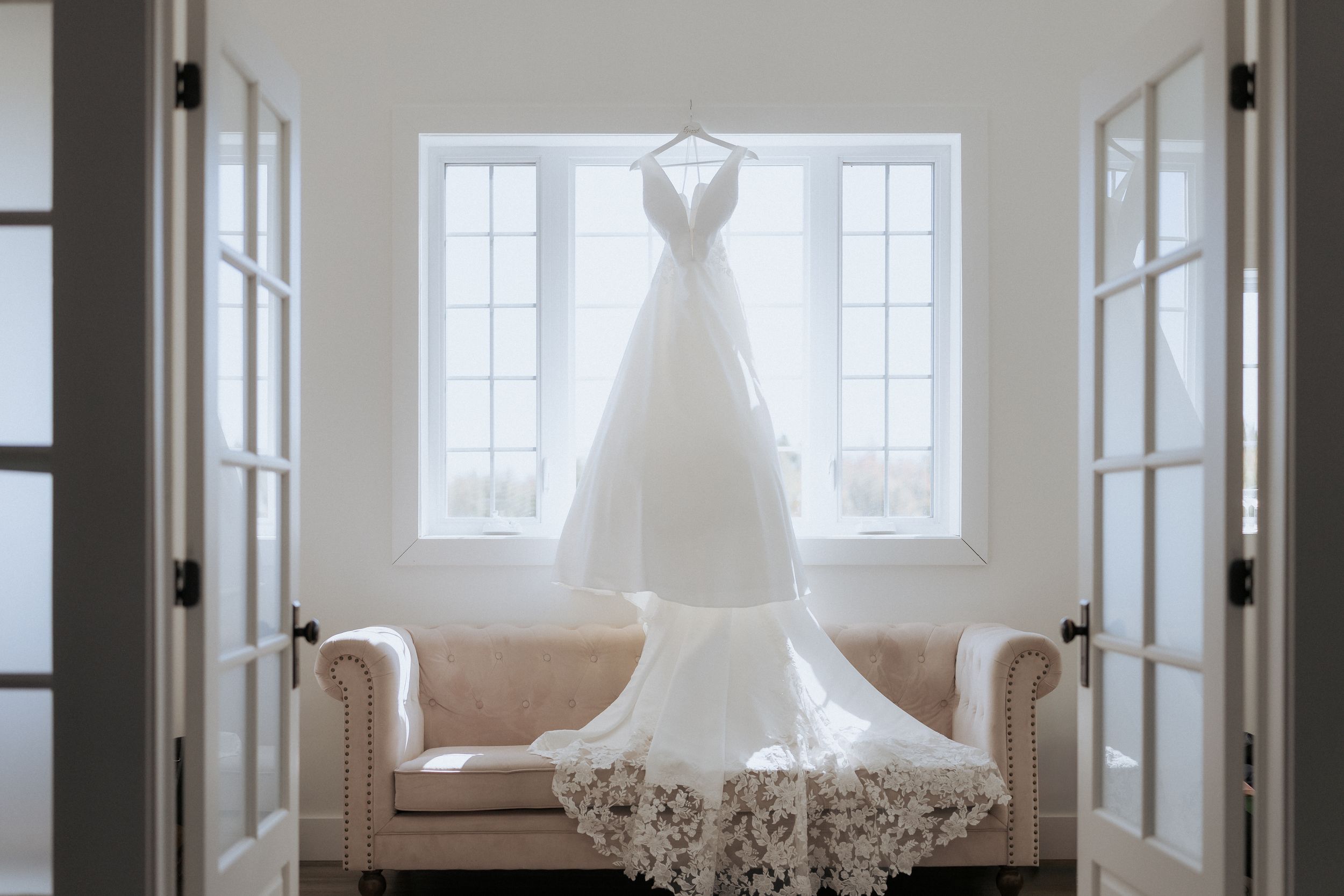 Elegant wedding dress hangs in the window at the Grand Ivory, New Brunswick wedding photographer, experienced photographer, timeless wedding