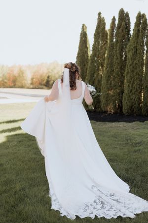 Bride walks in her wedding gown with the lace train behind her during outdoor fall wedding at the Grand Ivory, Moncton wedding photographer